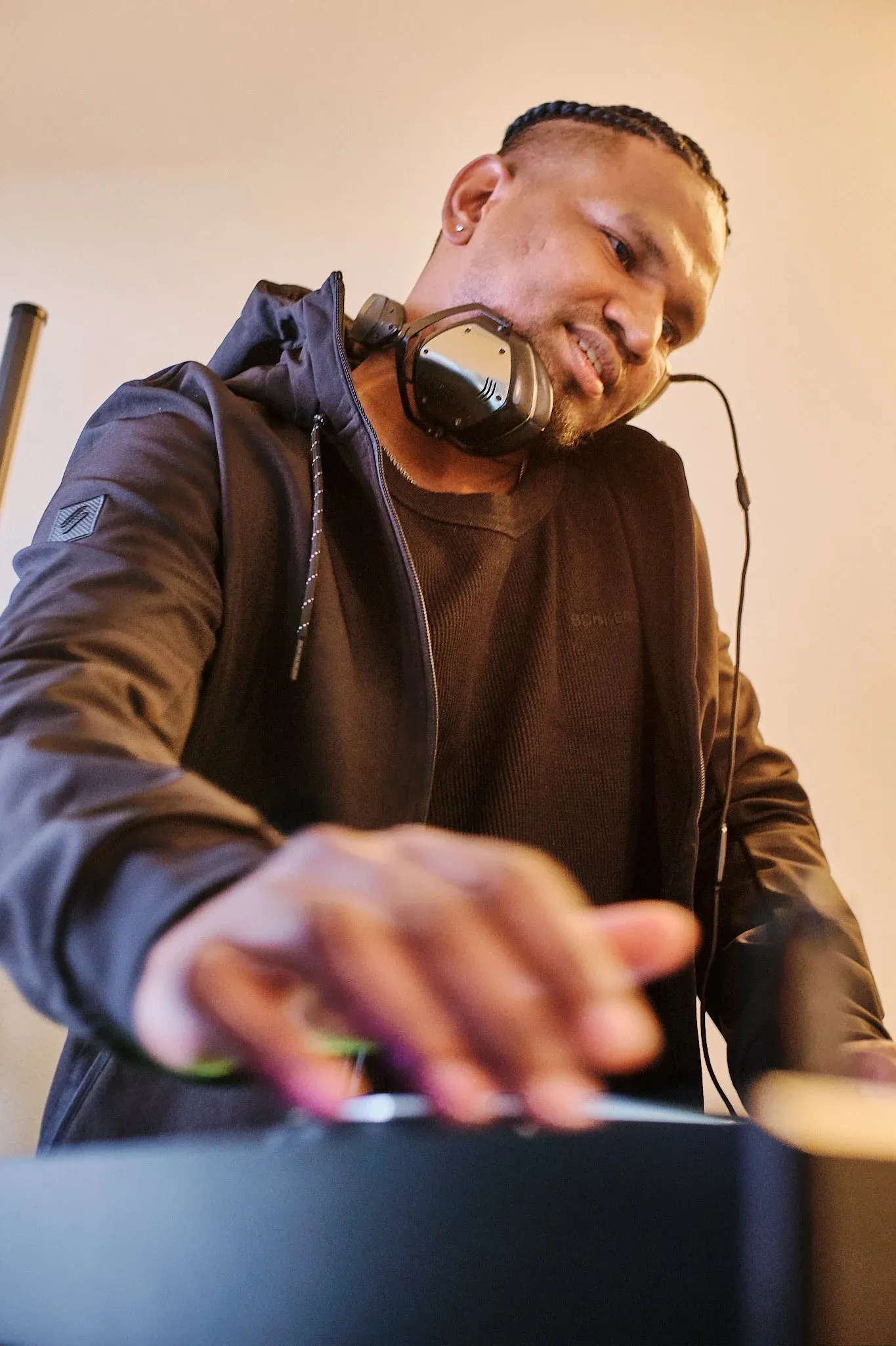 DJ with headphones around neck operating turntables at a music event.