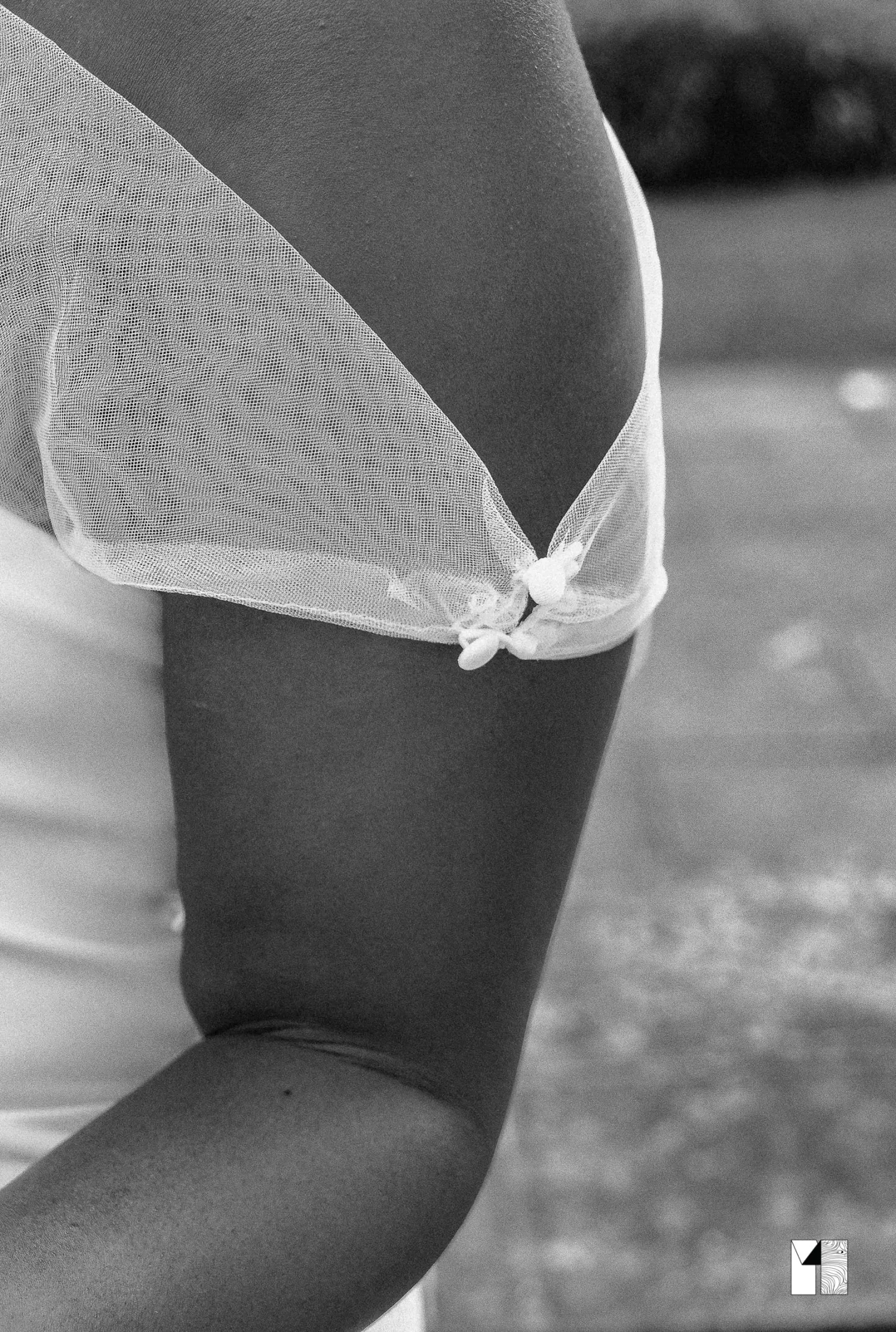 Black and white close-up of bride's shoulder detail with sheer tulle and bow on white gown.