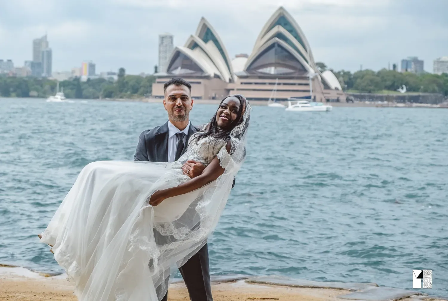 Bride and groom posing in front of Sydney Opera House on their wedding day.