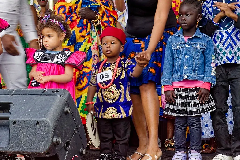 Children in traditional African attire at a multicultural outdoor festival event.
