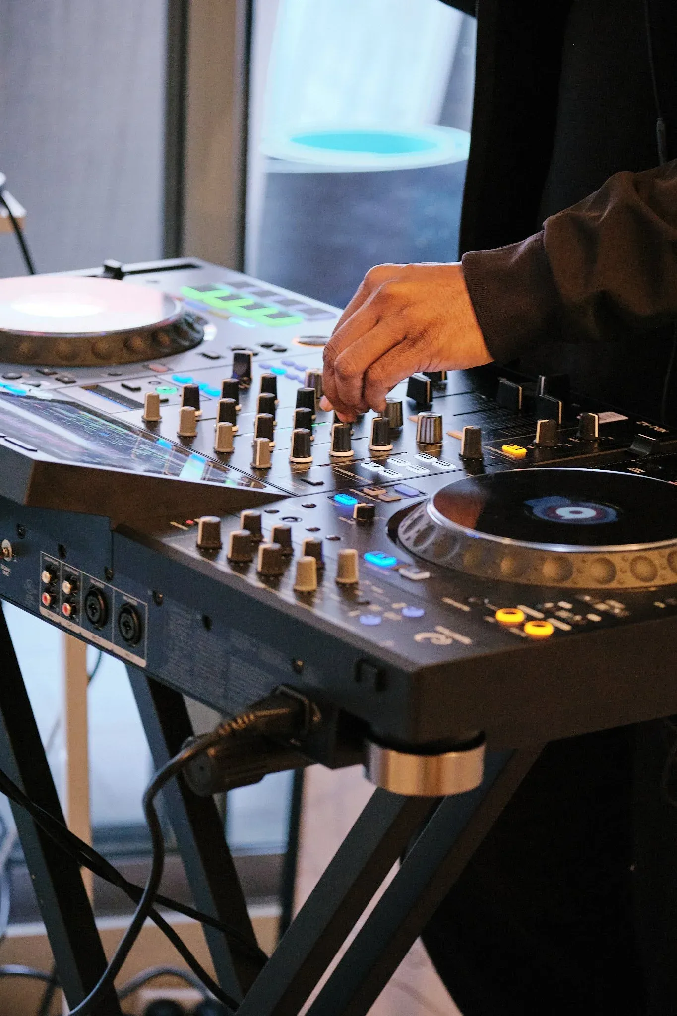 Close-up of hands adjusting controls on a professional DJ mixer setup.