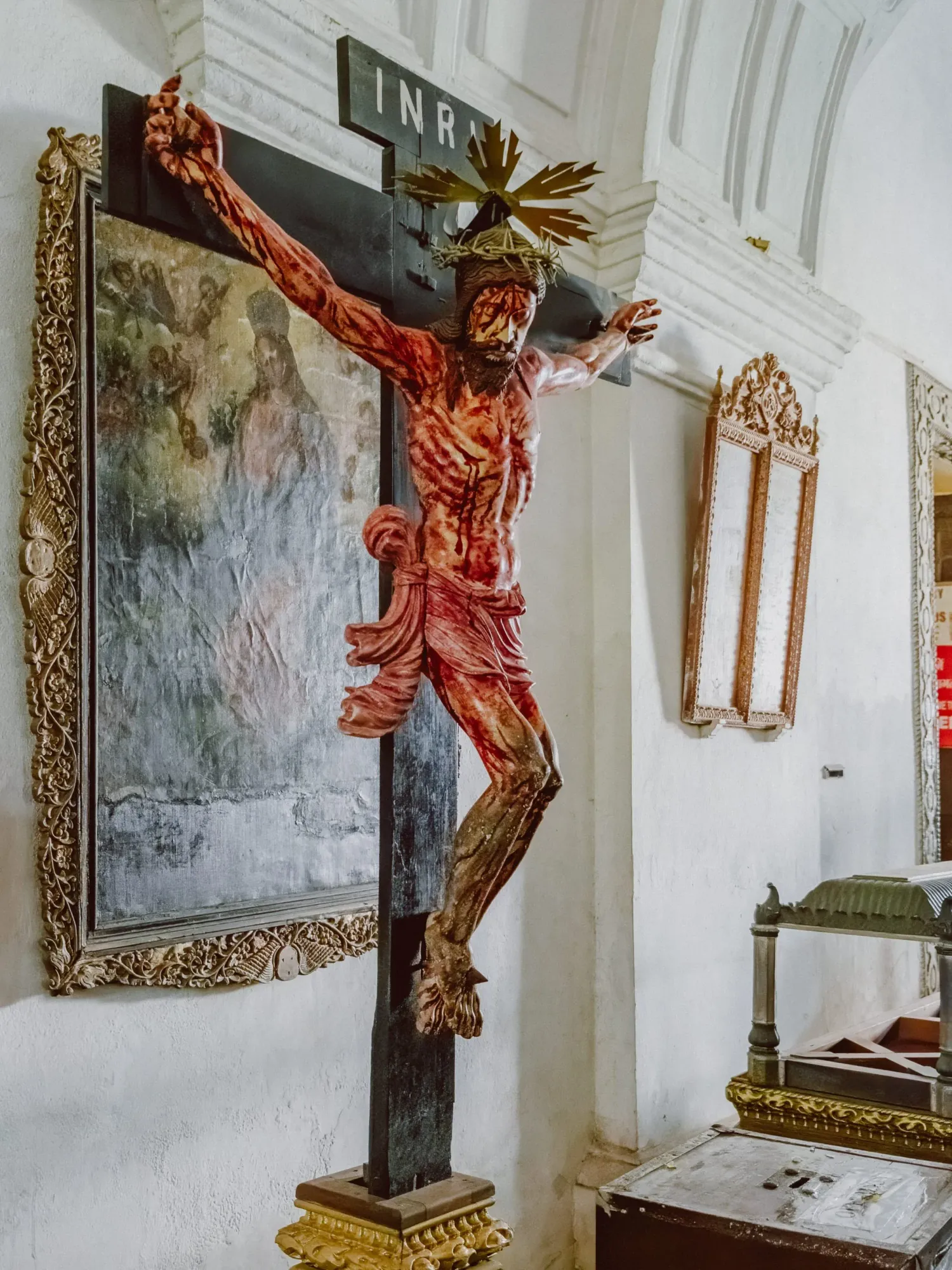 Detailed religious crucifix sculpture of Jesus Christ on cross inside white church interior.