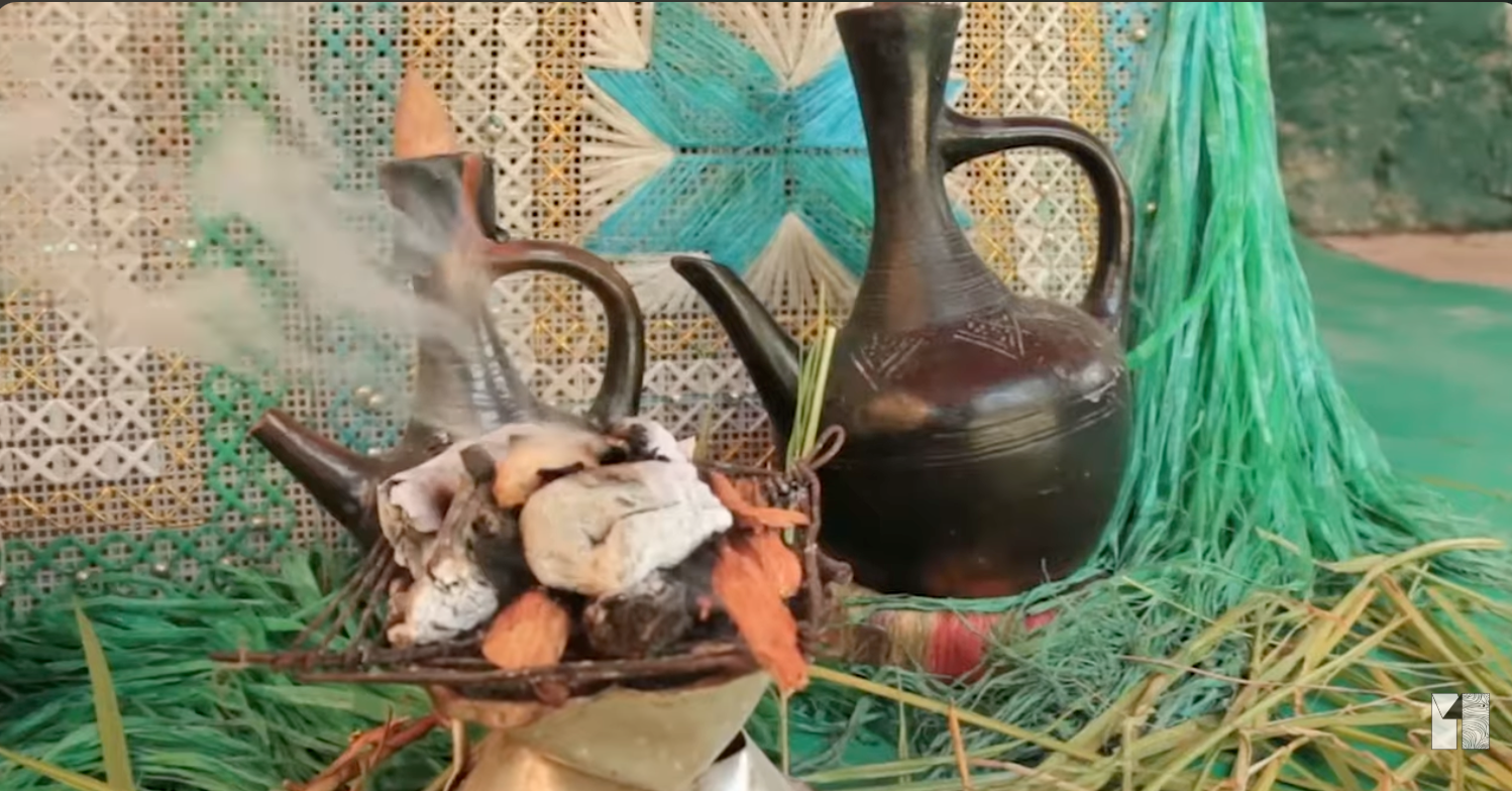 Traditional ceramic pottery and decorative items arranged with dried herbs and vegetables on a woven mat.
