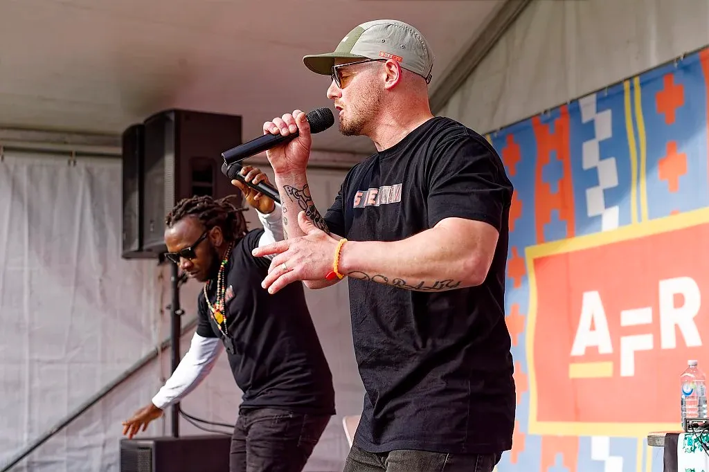 Two performers on stage, one rapping into a microphone at an African cultural festival.
