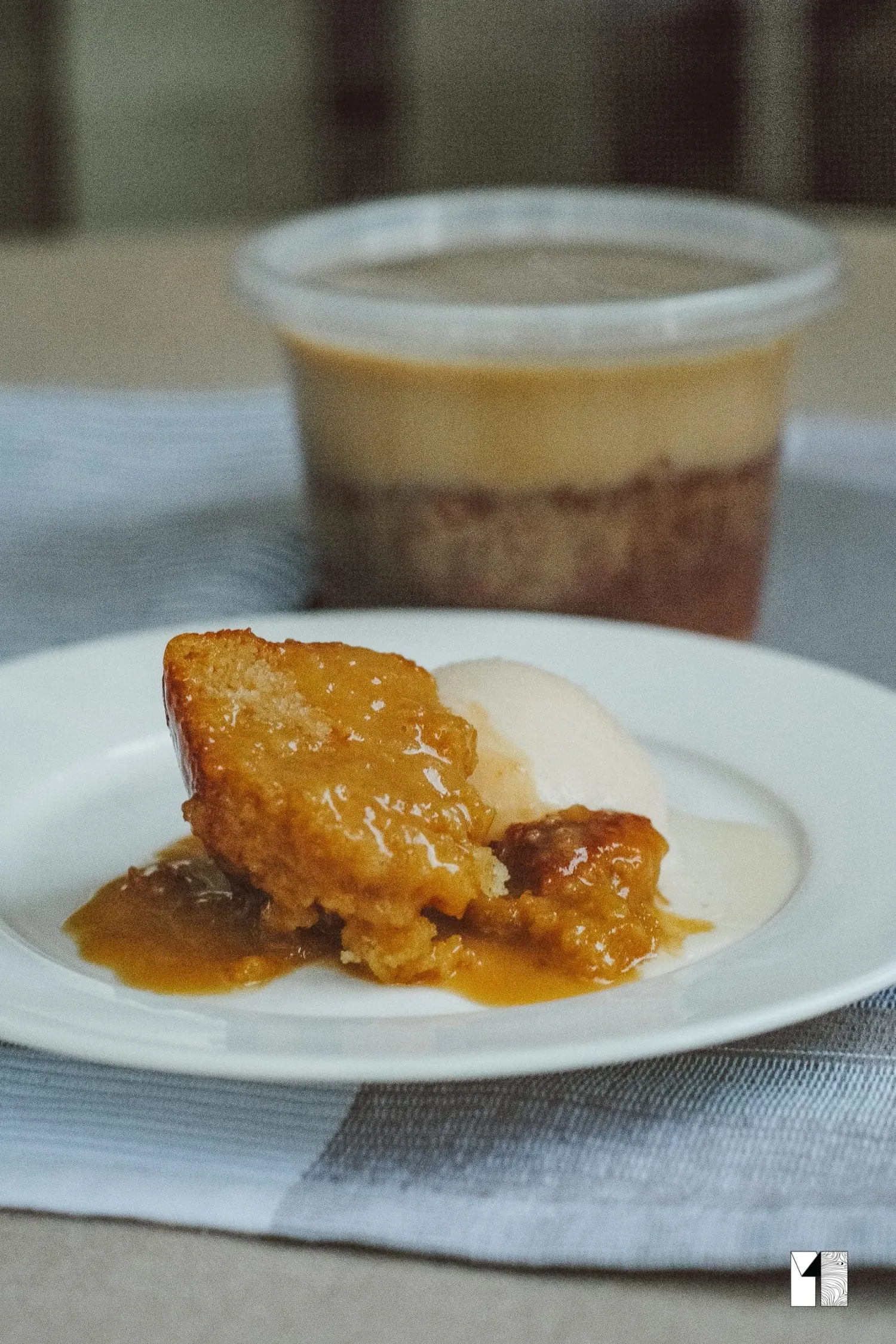 Warm sticky toffee pudding with caramel sauce and vanilla ice cream on a white plate.