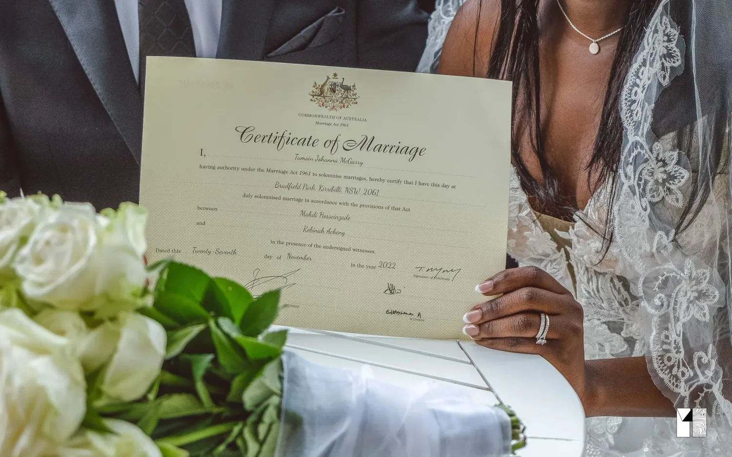 Bride holding Australian Certificate of Marriage with white roses nearby.