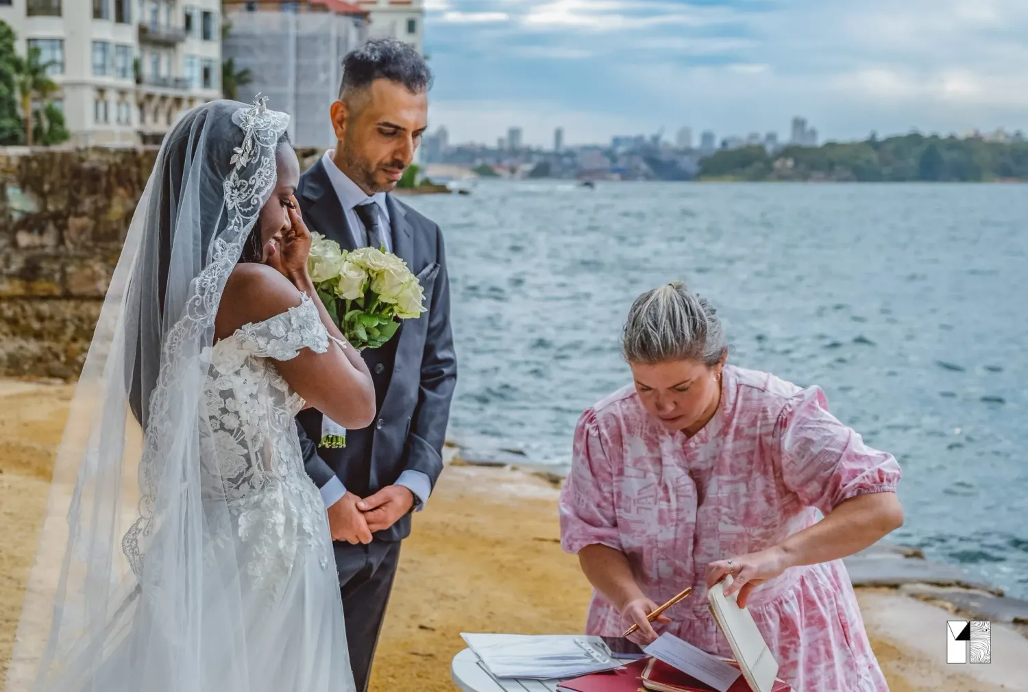 Bride and groom exchanging vows with officiant by Sydney Harbour waterfront wedding ceremony.