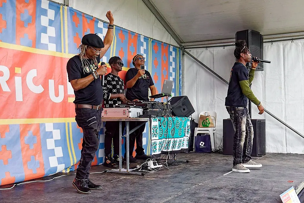 African music artists performing on stage with DJ equipment at multicultural outdoor festival.
