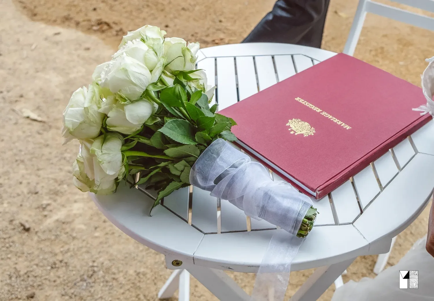White rose bouquet and red marriage certificate on a white table.