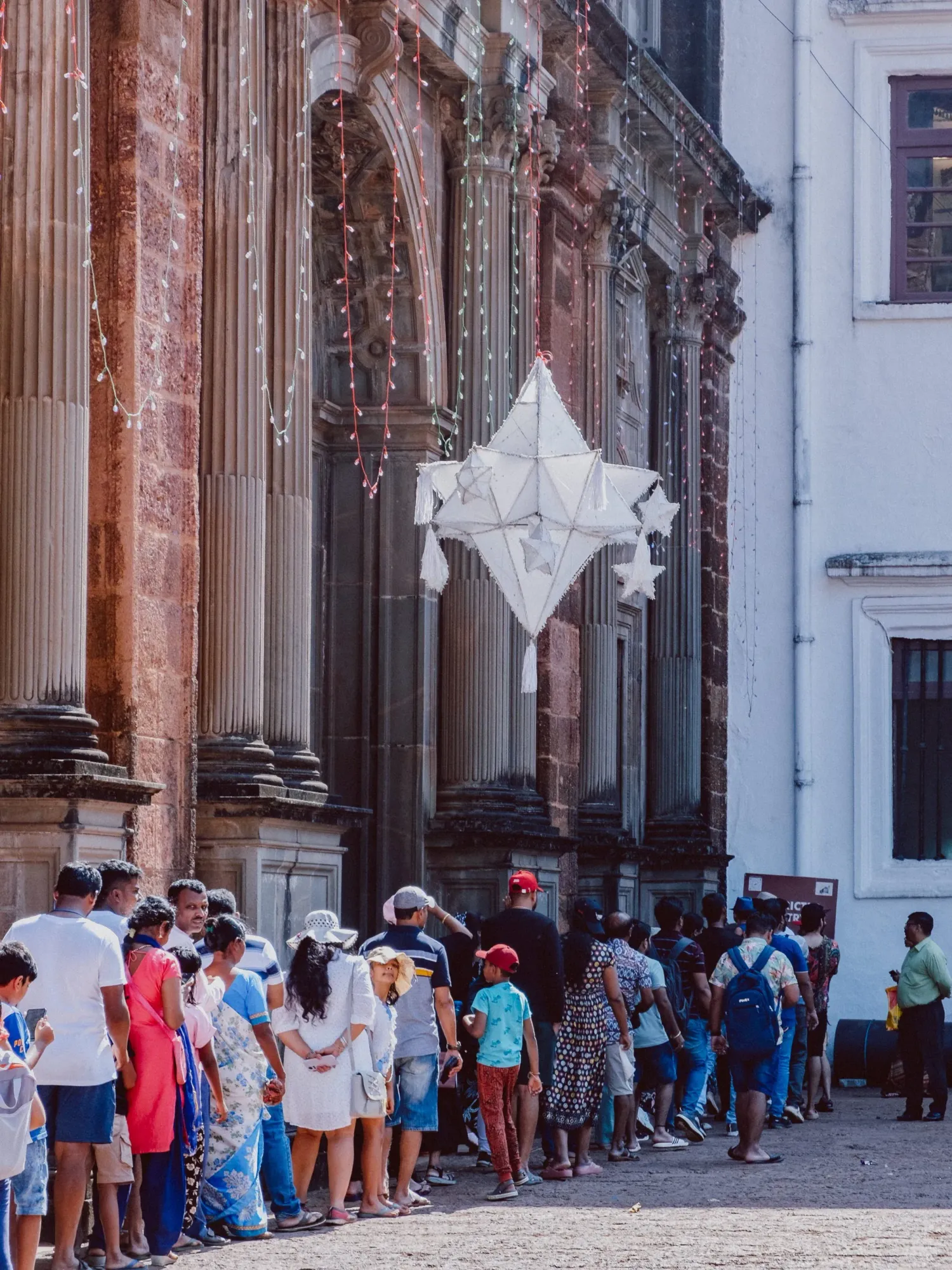 Crowd of tourists queuing outside ornate historic colonial church facade with star decoration.