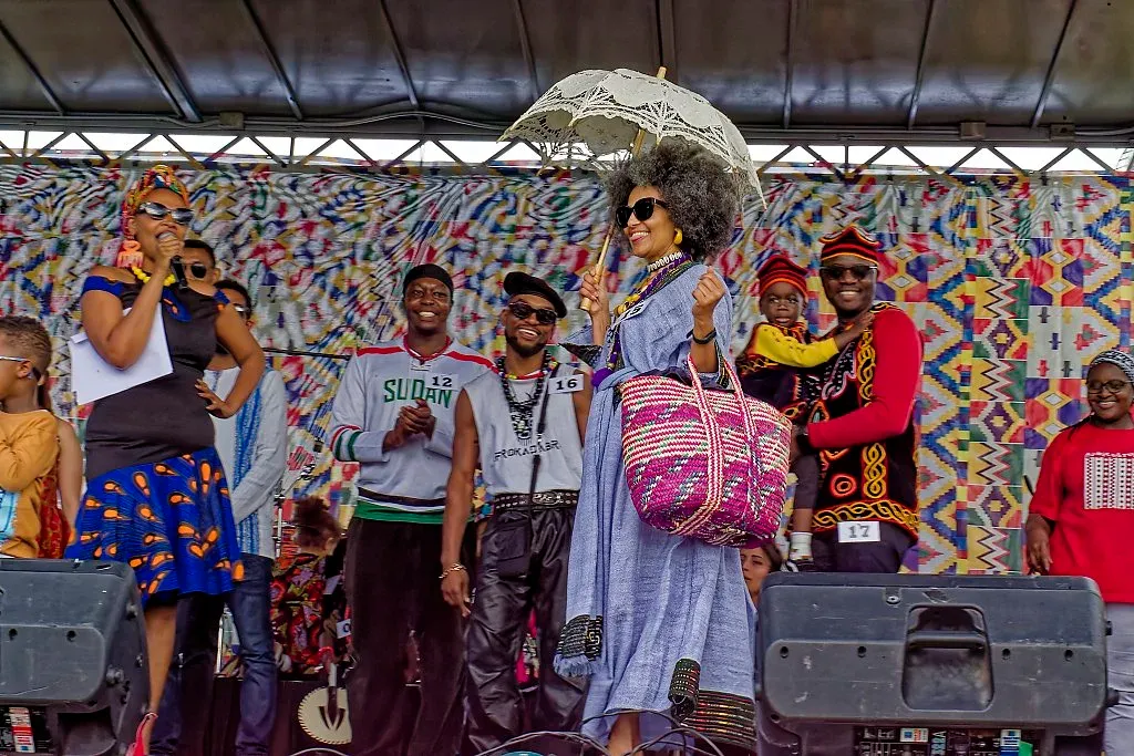 Diverse group of performers in traditional African attire on a festival stage.
