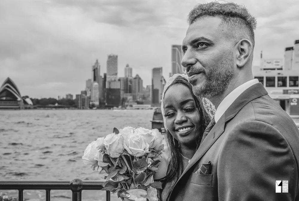 Couple poses romantically with Sydney Opera House skyline backdrop on their wedding day.