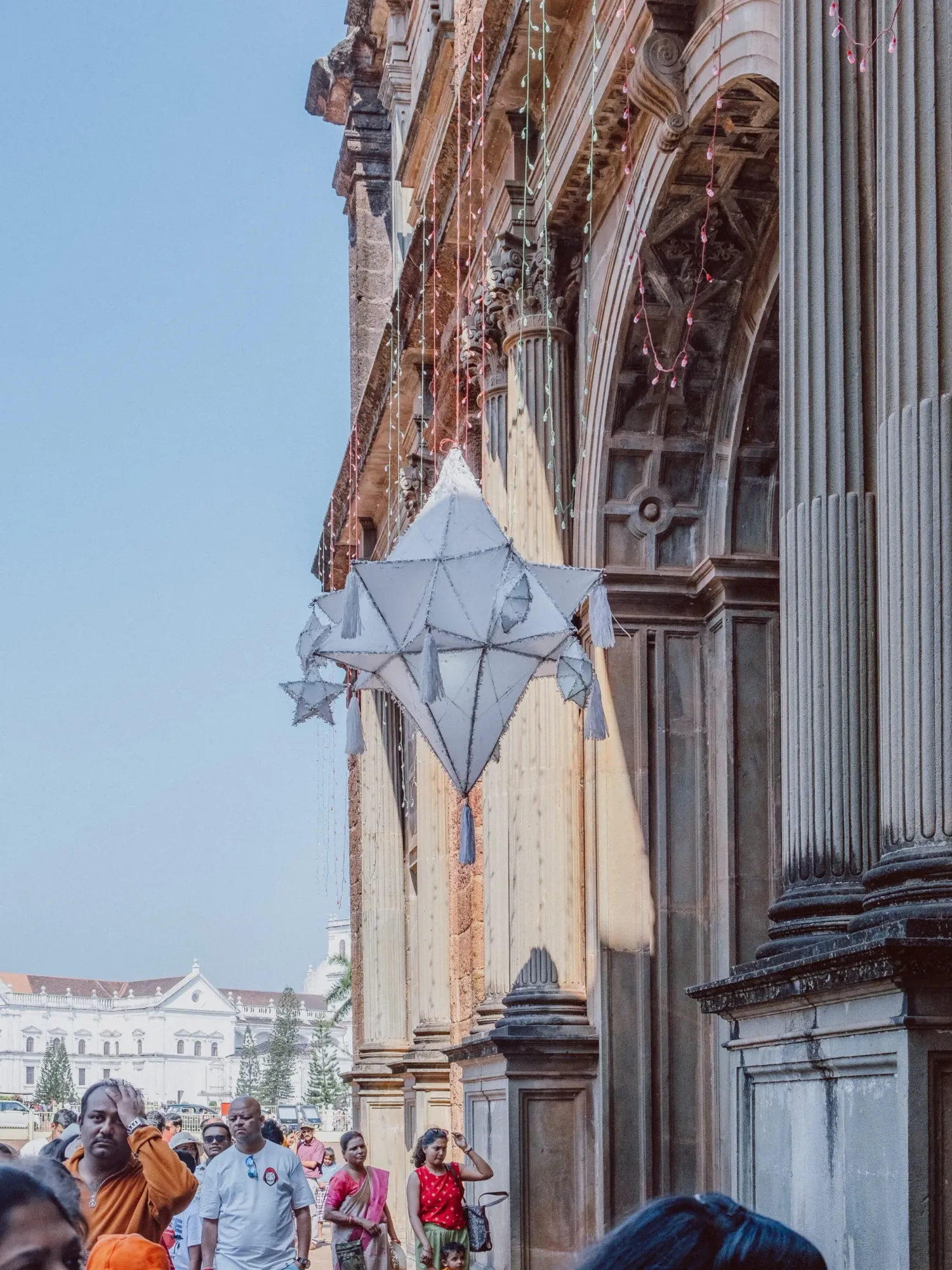 Geometric paper star lantern hanging outside an ornate colonial church facade with visitors below.