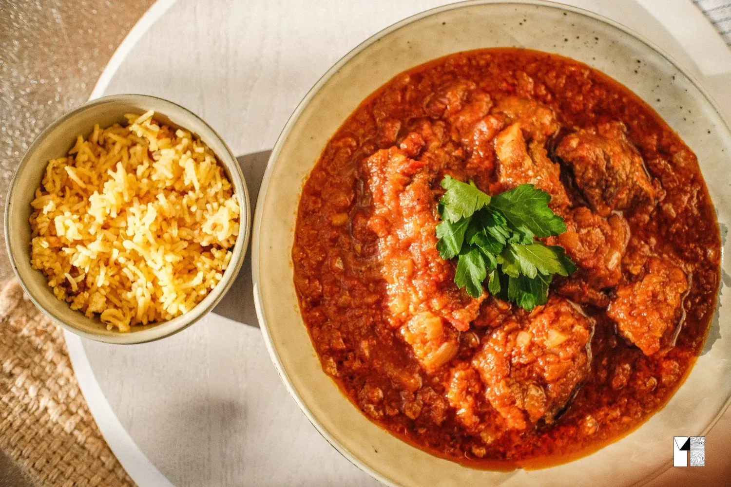 Spicy tomato chicken stew garnished with cilantro served with a side of rice.
