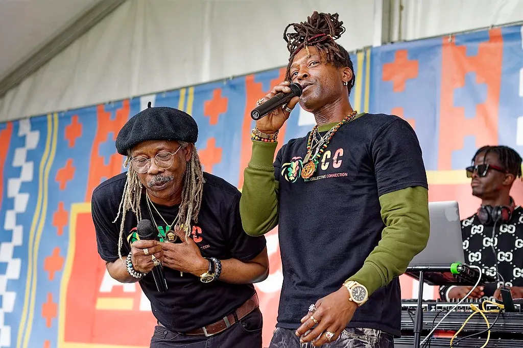 Two male artists performing together on stage at a vibrant outdoor music festival.