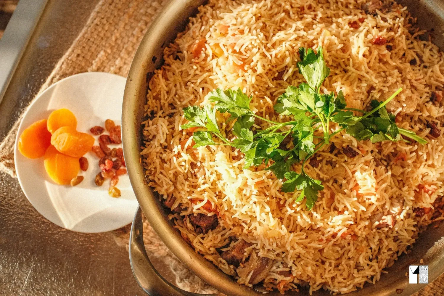Aromatic basmati rice dish garnished with fresh cilantro and dried apricots served in a traditional cooking pot.