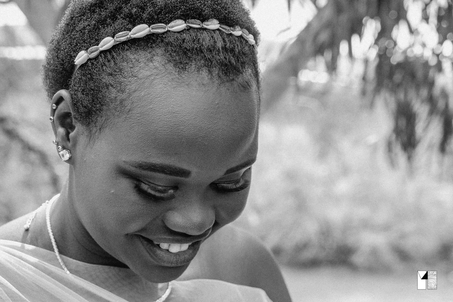 Black and white close-up portrait of a smiling bride wearing a delicate headband.