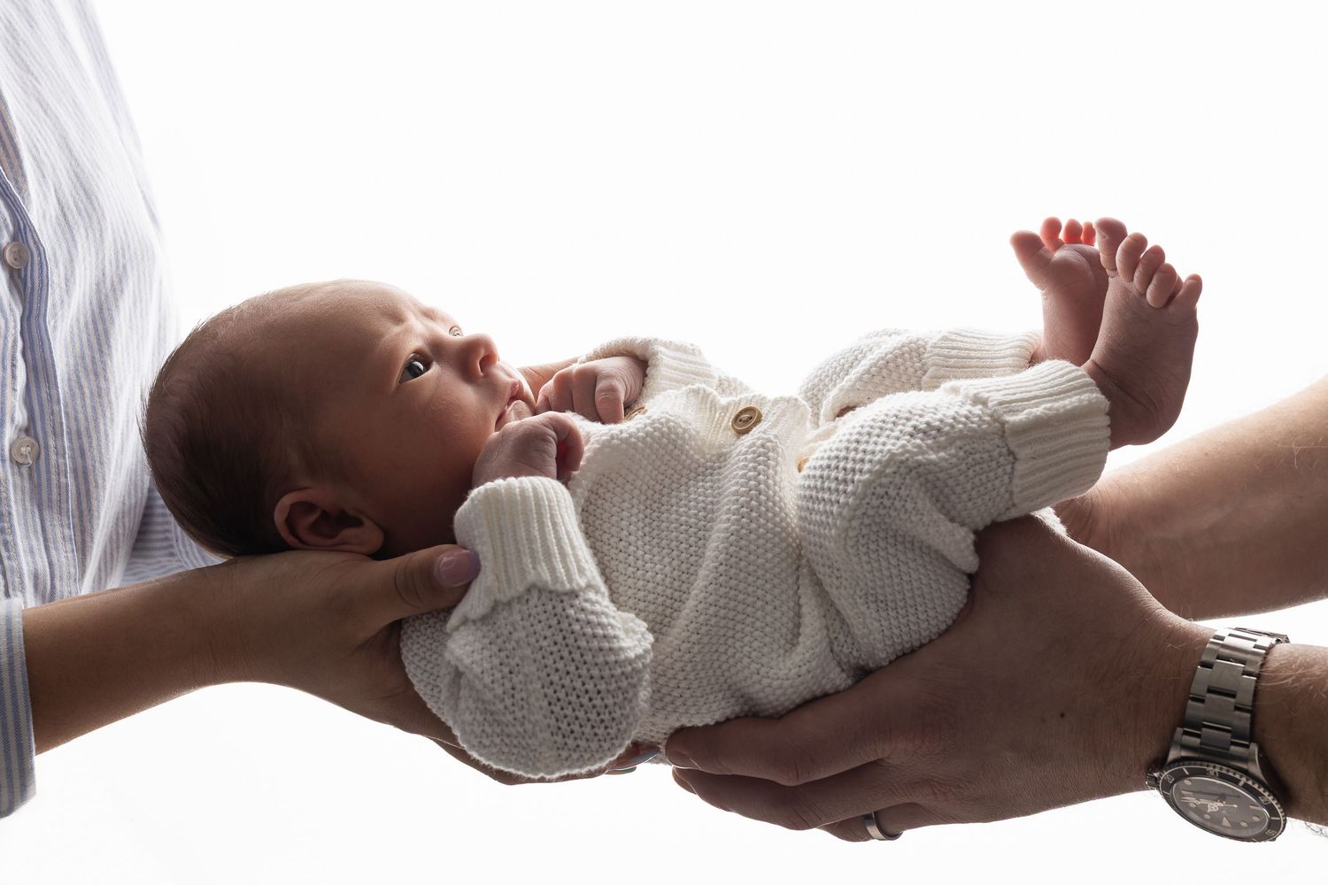 Back lit photo of baby in parents hand
