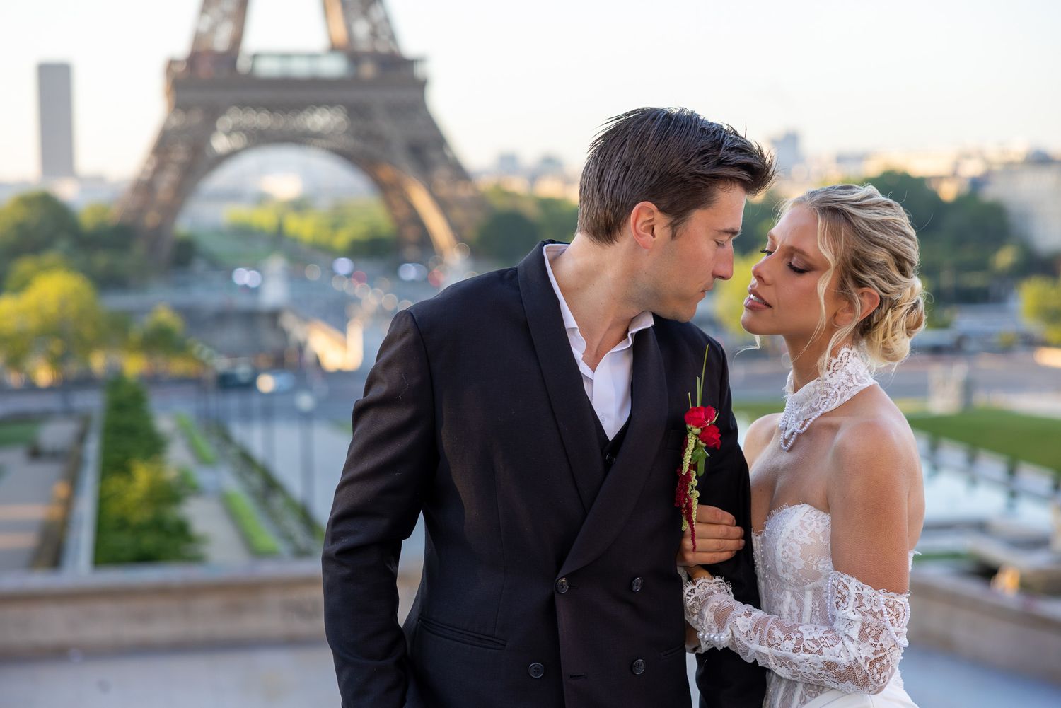Groom holds a red rose while sharing an intimate moment with bride near Eiffel Tower.