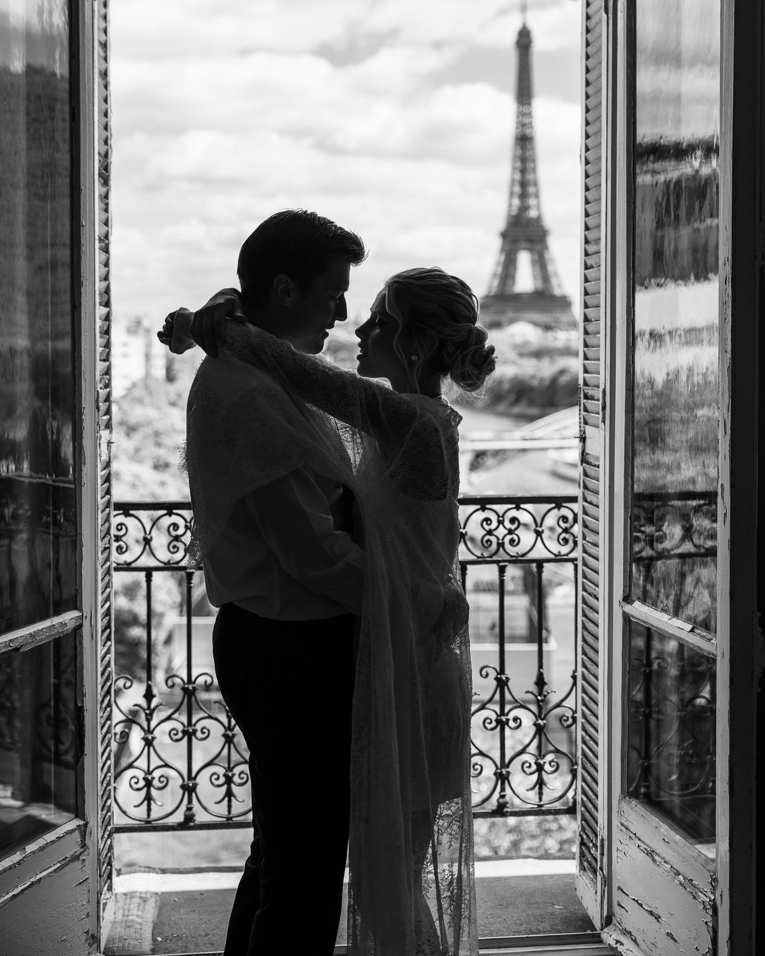 Silhouette of bride and groom embracing in doorway with Eiffel Tower backdrop.