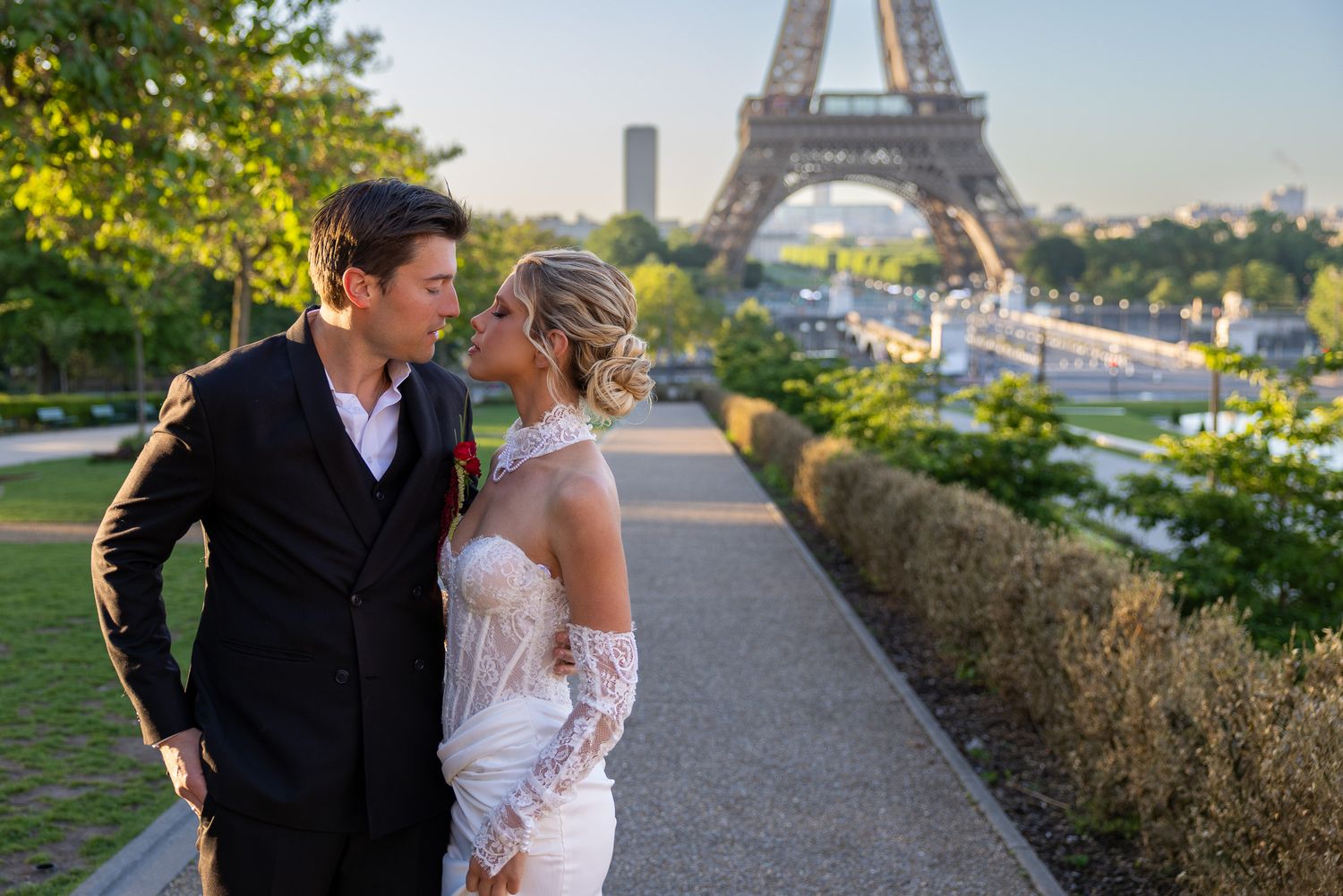 Newlyweds sharing intimate moment on pathway with Eiffel Tower in background Paris.