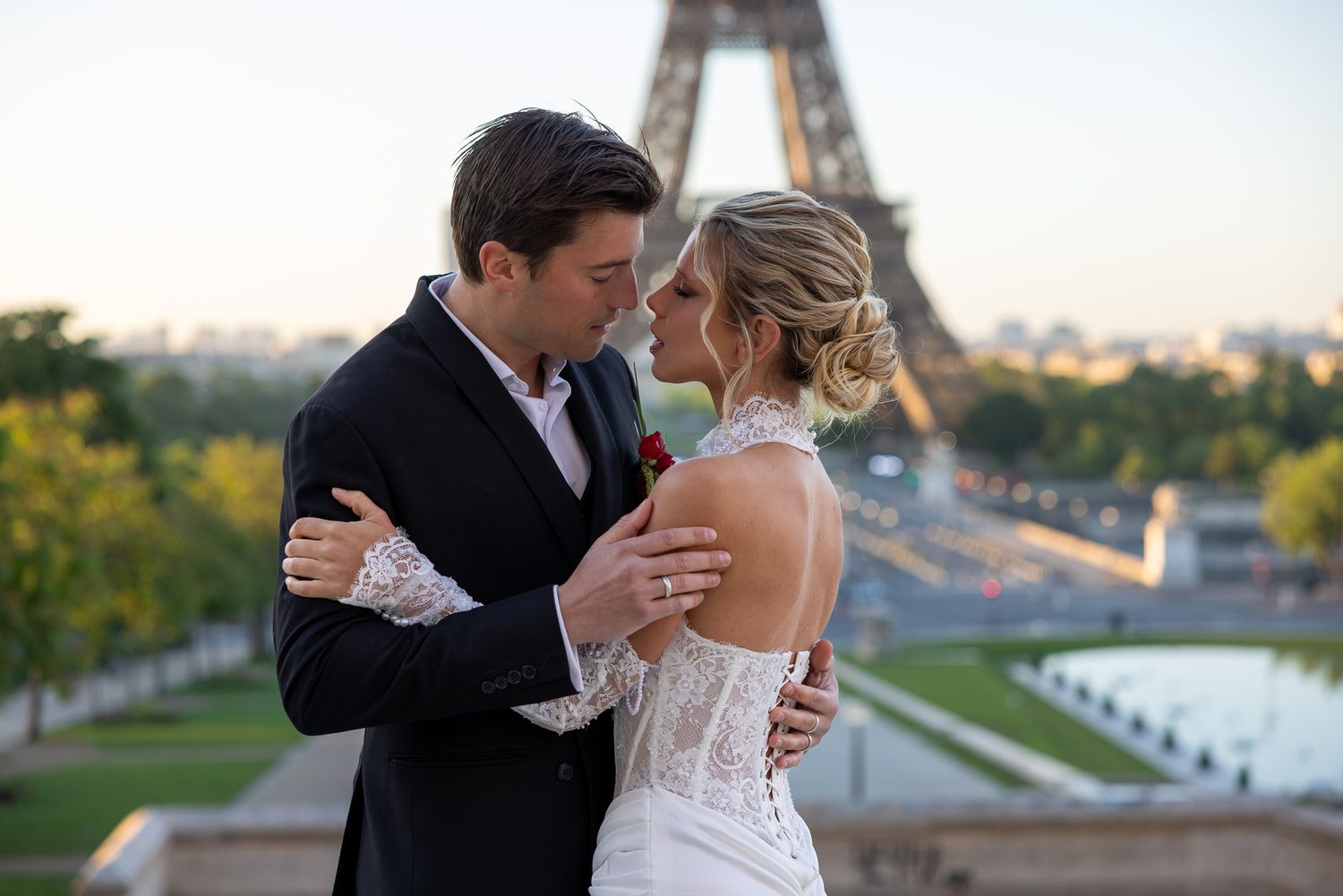 Bride and groom embrace romantically with the Eiffel Tower at sunset in Paris.