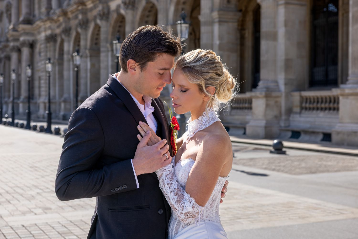 A bride and groom share a romantic moment outside a grand classical building in Paris.