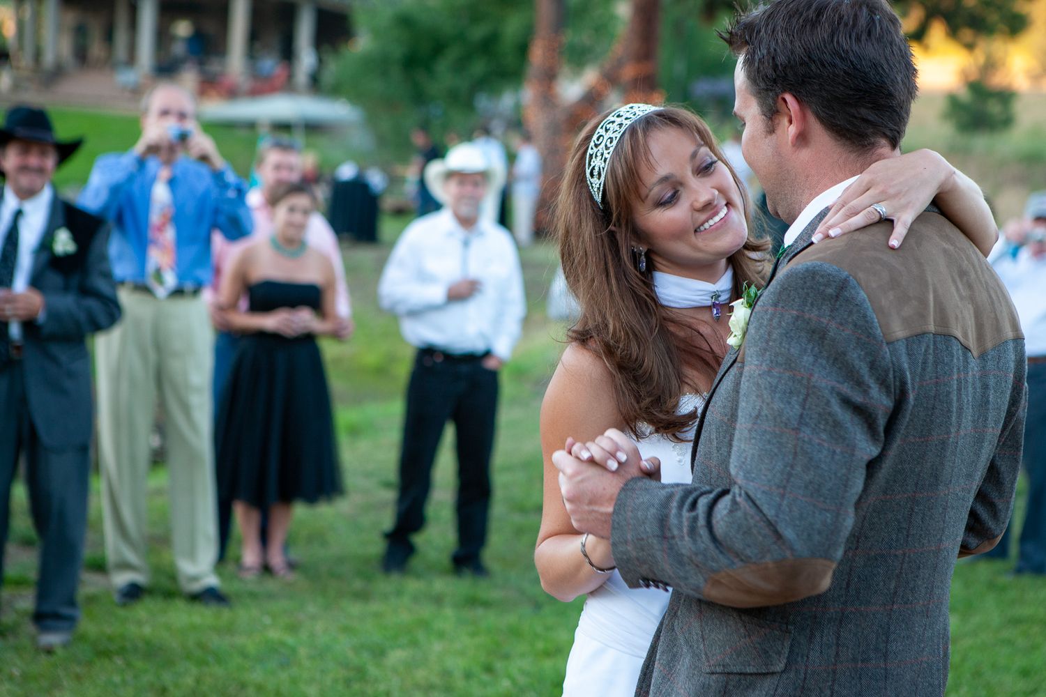 Bride and groom sharing their first dance outdoors at a wedding reception with guests watching.