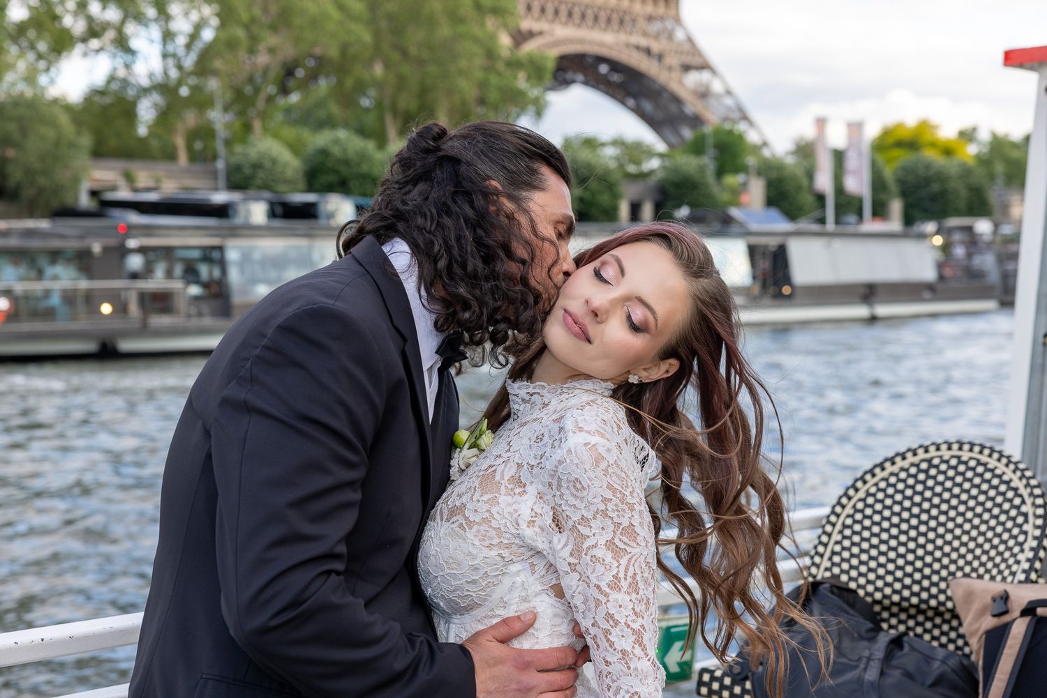 Groom kissing bride tenderly on the cheek near the Eiffel Tower in Paris.