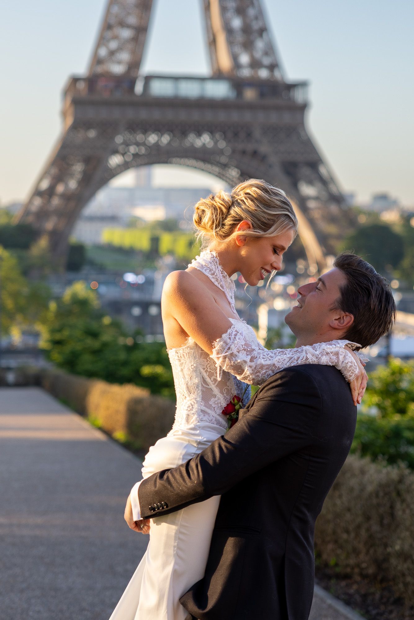 Groom lifts bride in front of the Eiffel Tower during a romantic Paris wedding photo session.