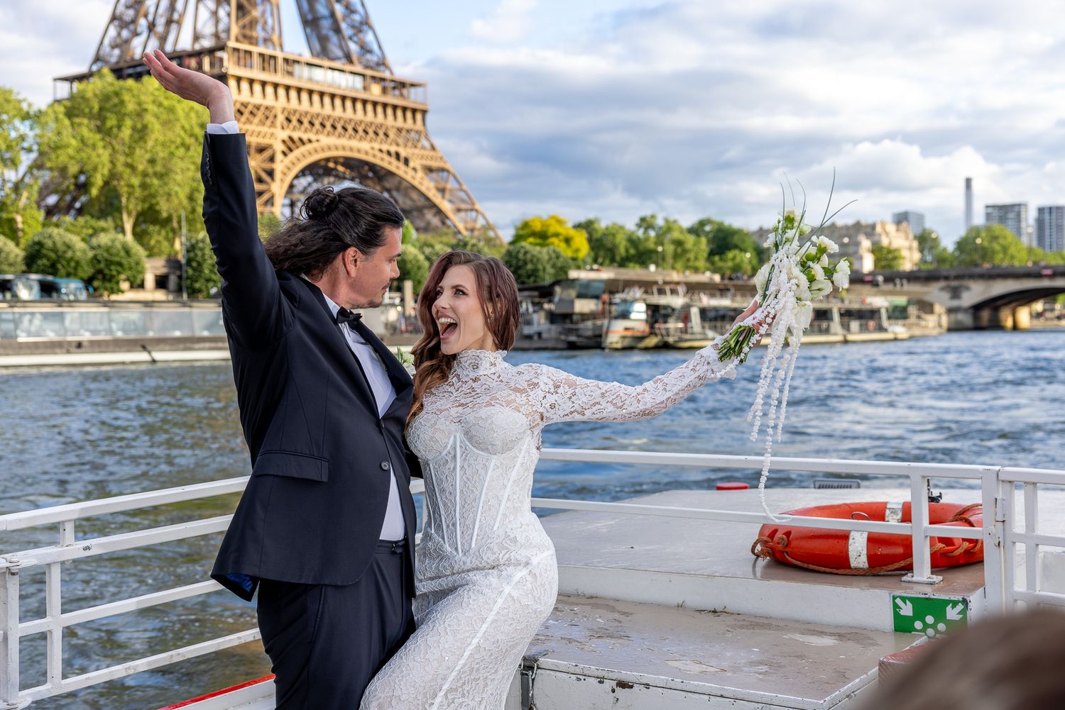 Joyful newlyweds celebrate on Seine River boat with Eiffel Tower in background.