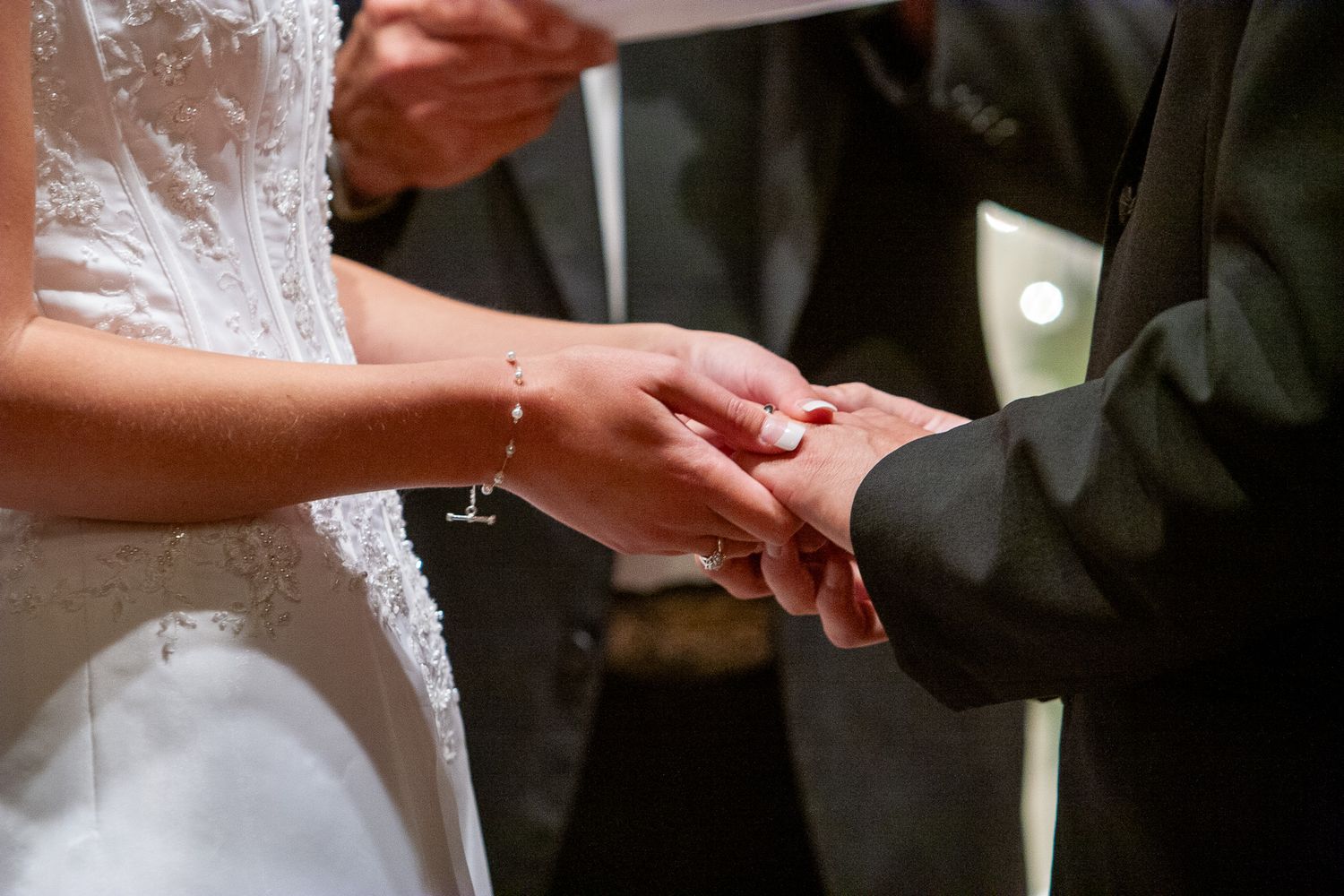 Bride placing a wedding ring on the grooms finger during the marriage ceremony.