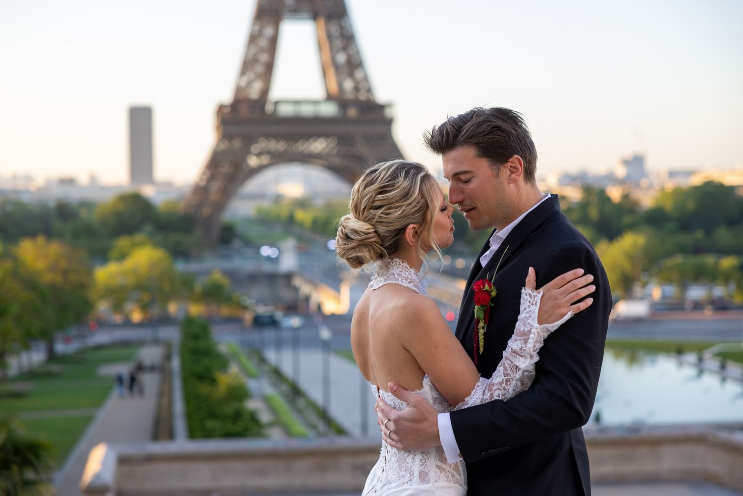 Newlyweds share a tender kiss with the iconic Eiffel Tower glowing at sunset.