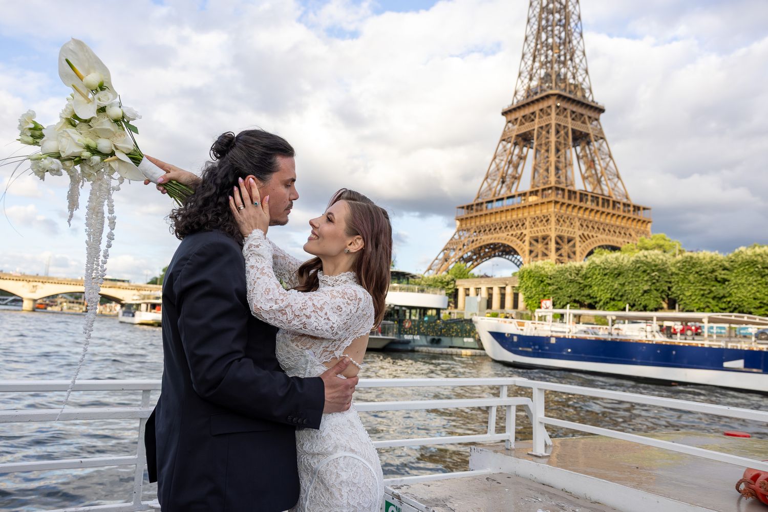 Wedding couple embracing on a Seine river boat with the Eiffel Tower behind them.