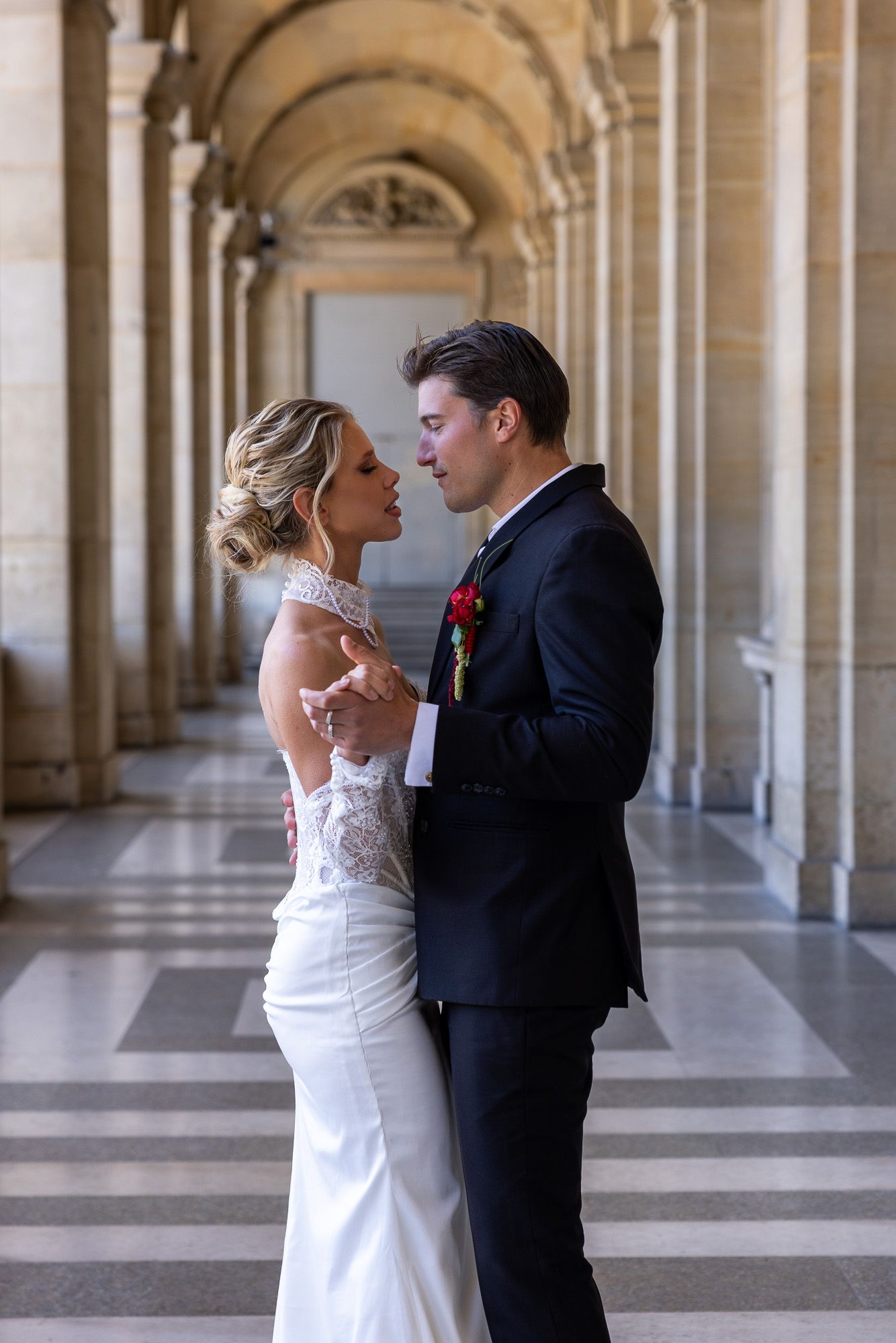A bride and groom share an intimate dance in a grand arched hallway in Paris.