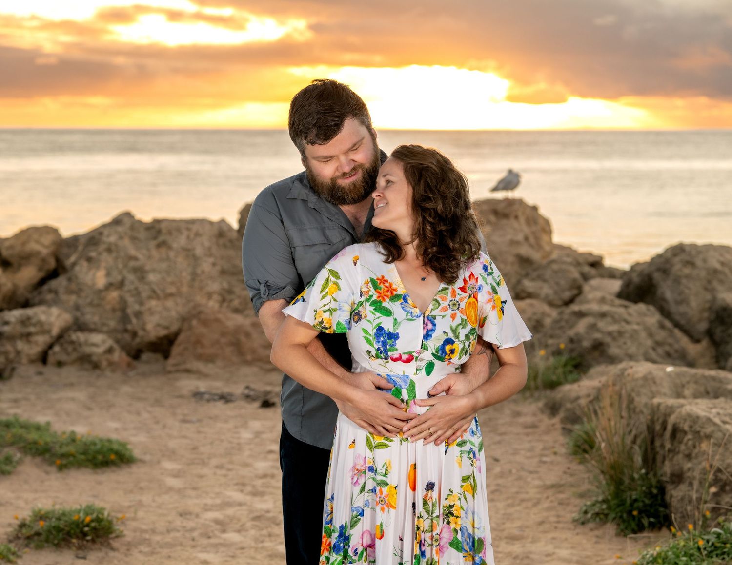 Expecting parents smiling while sharing their pregnancy announcement outdoors.