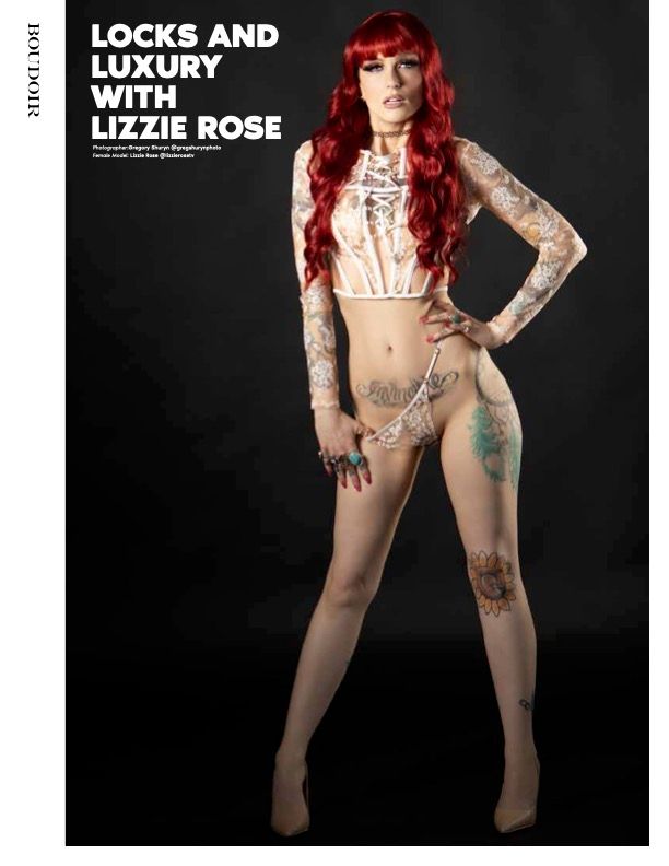 Heavily tattooed model Lizzie Rose poses in white lace lingerie with long red hair for Boudoir magazine editorial.