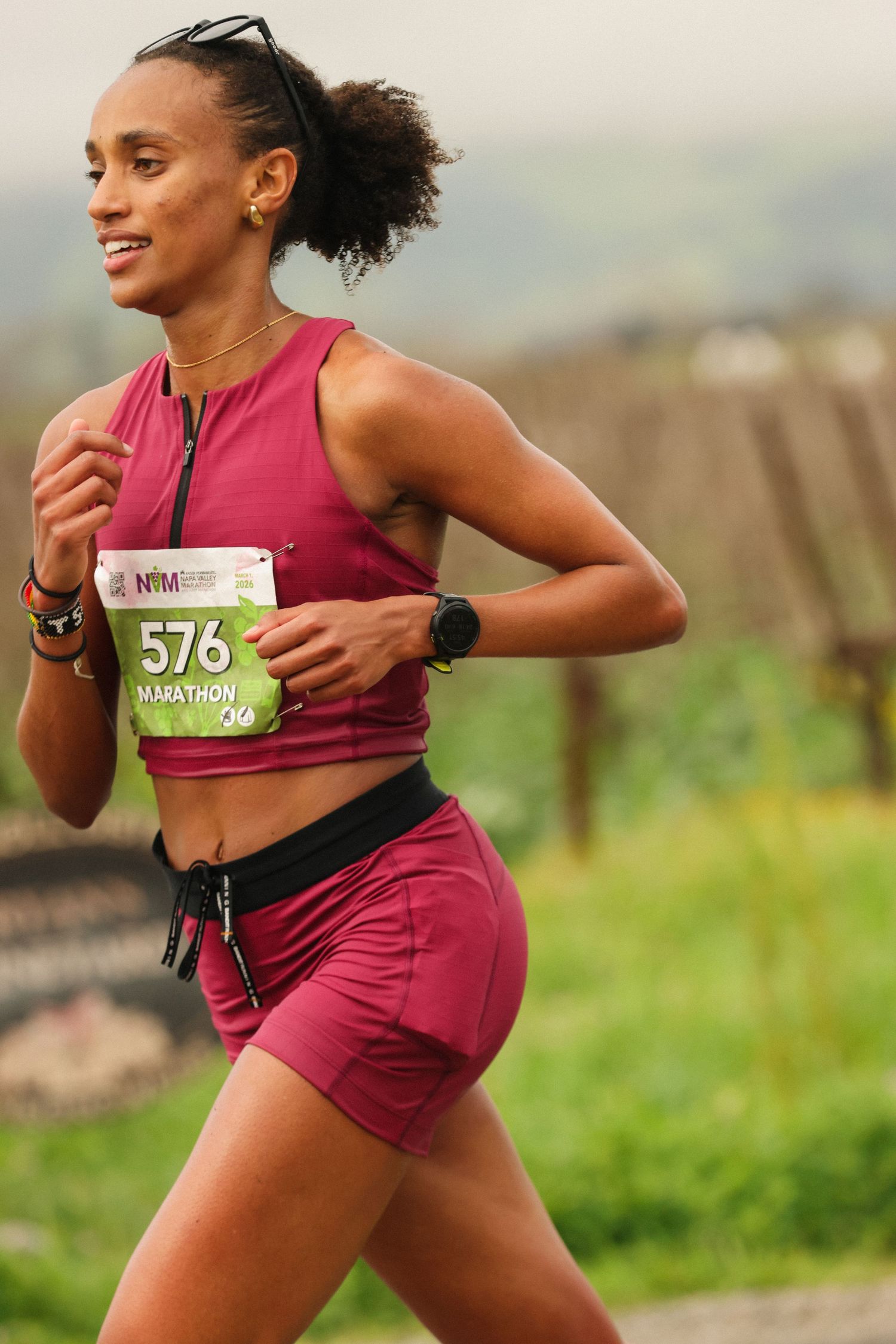Female runner wearing bib number 576 competes in a marathon through scenic countryside.