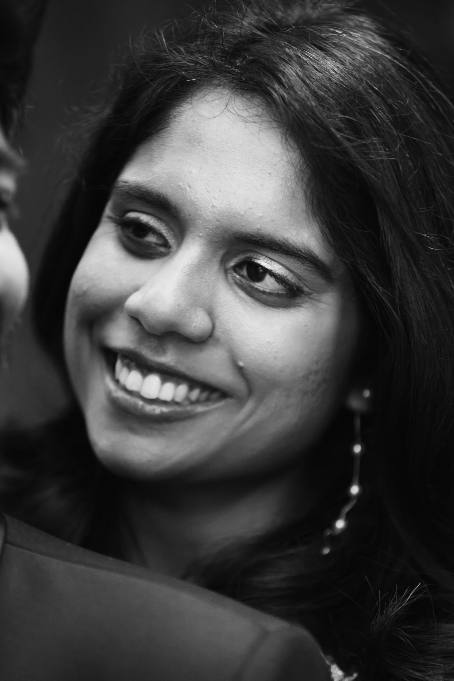 Black and white portrait of smiling Indian bride with dangling earrings at wedding.