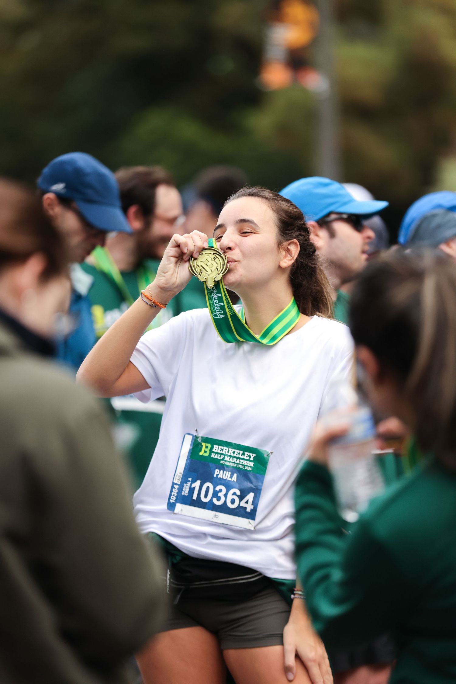 A young female runner kisses her gold finisher medal at the Berkeley Half Marathon.