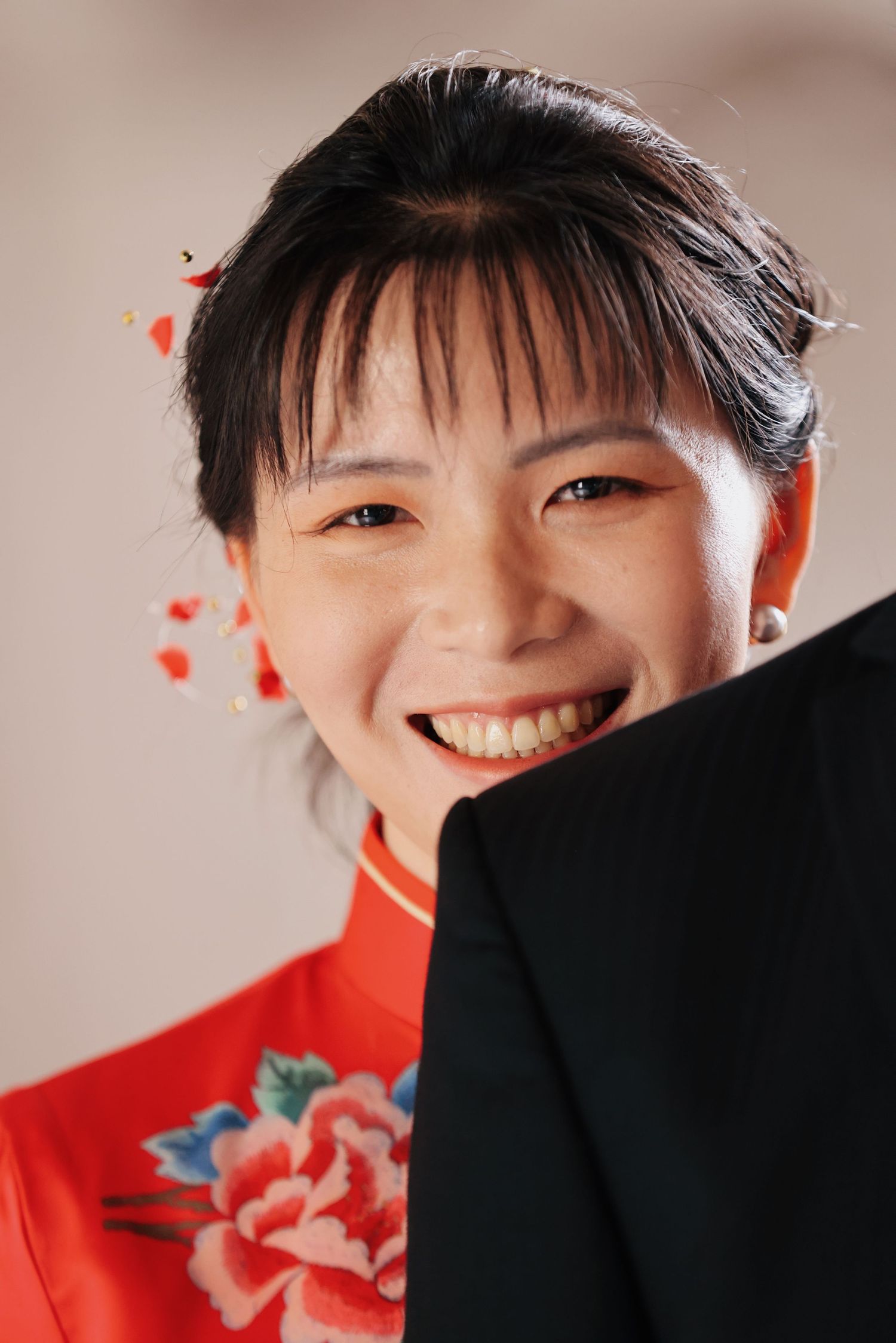 Happy Asian bride in red cheongsam laughing joyfully during wedding celebration.