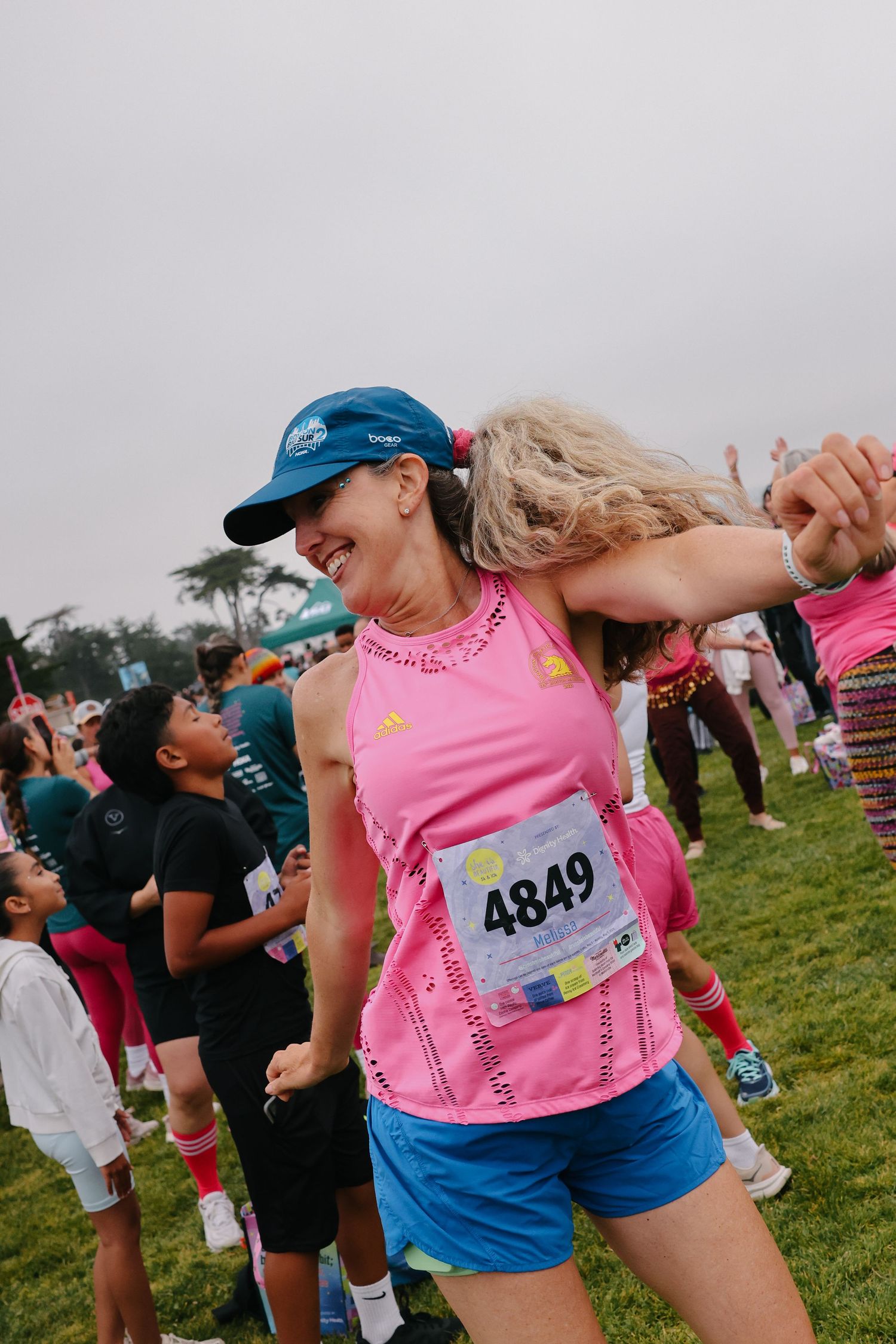 Joyful female runner wearing bib 4849 celebrating at an outdoor race event.