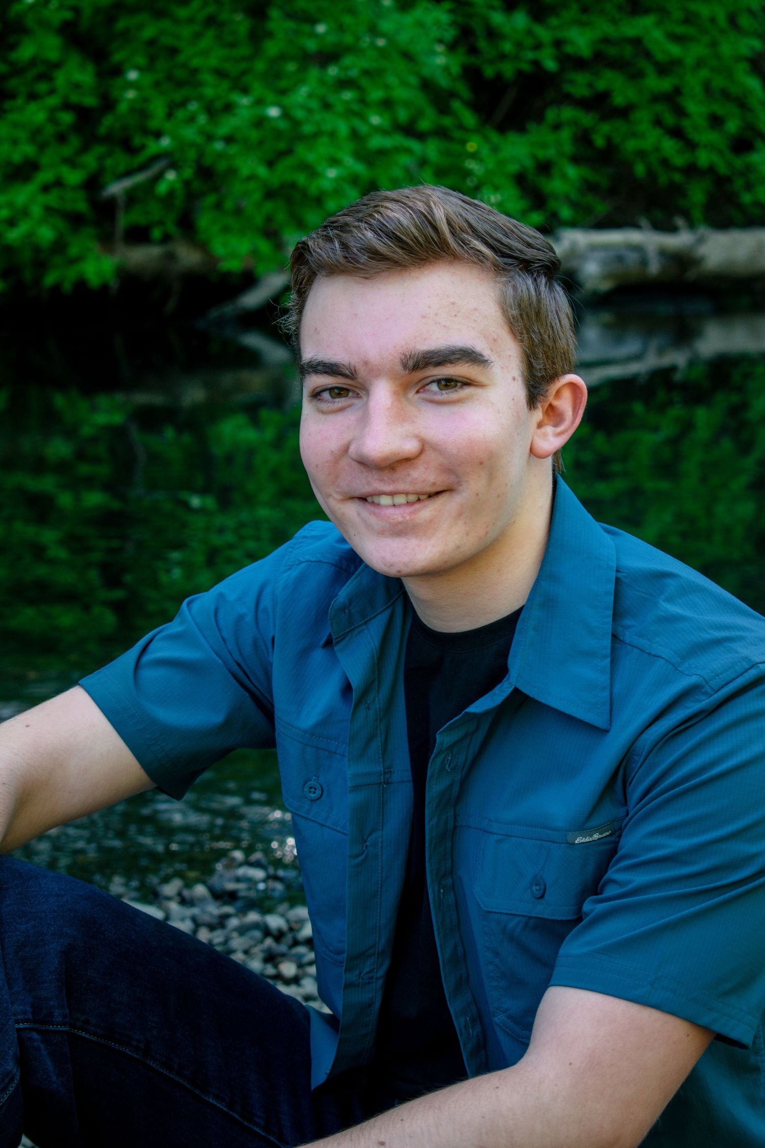 Close up of male posing in front of river during his senior session in Philomath Oregon.
