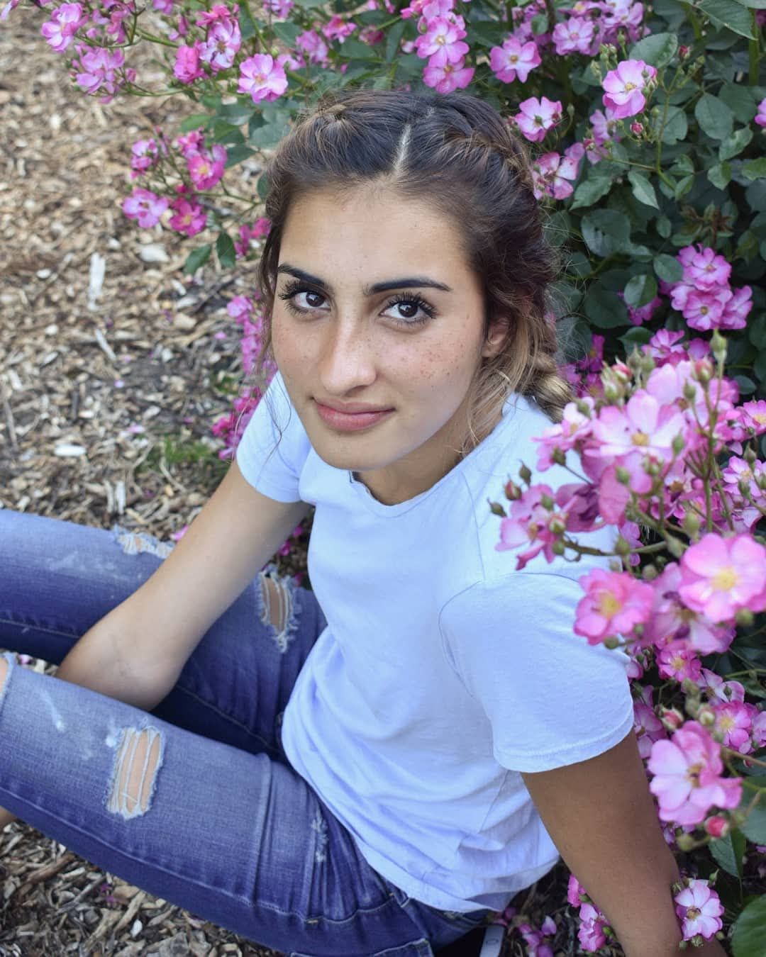Senior girl posing in front of flowers during her senior portrait session in Corvallis Oregon.