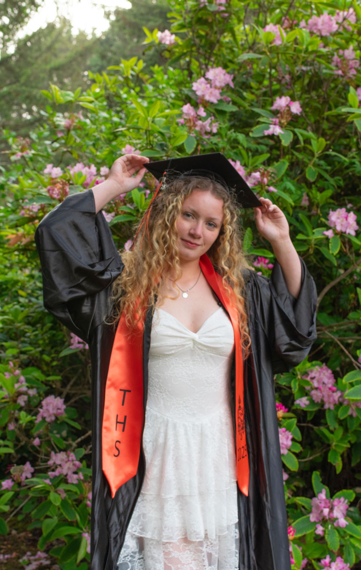 Female holding cap during cap and gown session in Depoe Bay Oregon.