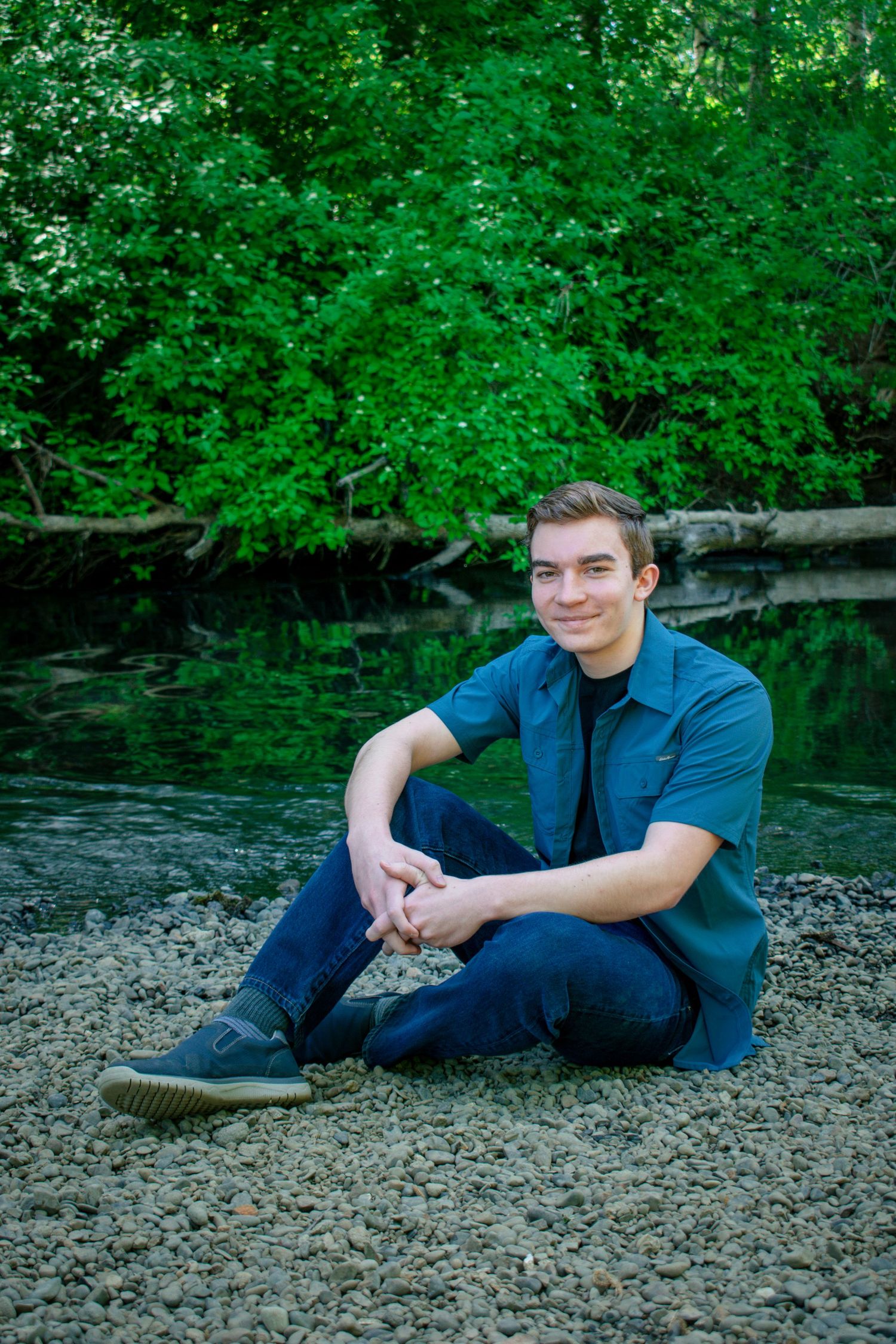 Male poses for his senior pictures in front of a river in Philomath Oregon.