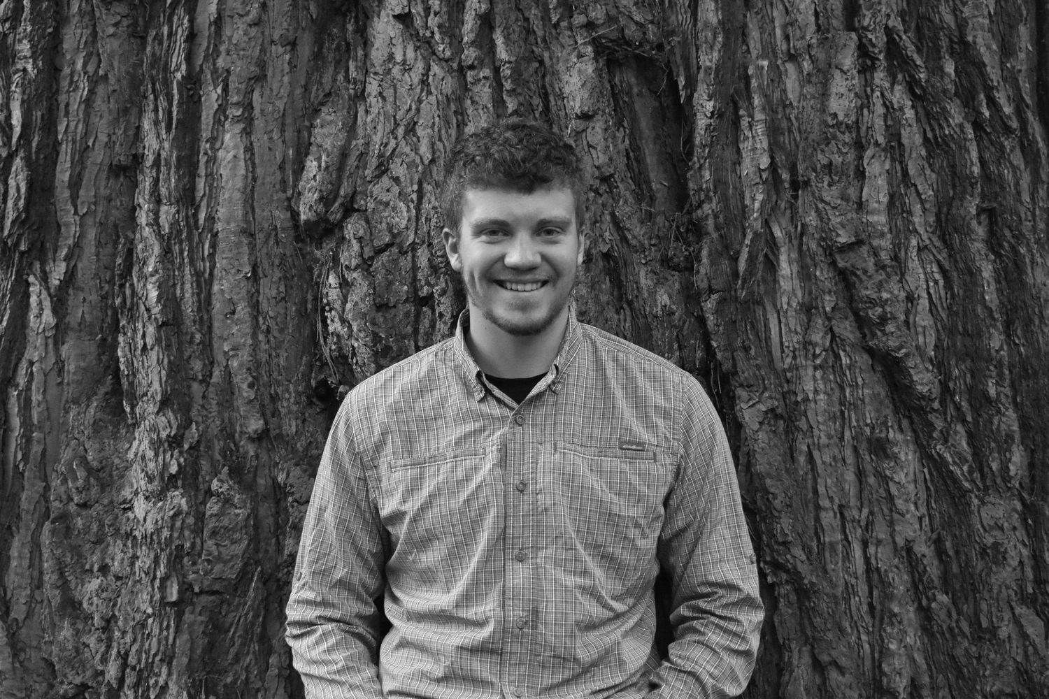 Male posing casually against tree for his senior pictures in Corvallis Oregon.