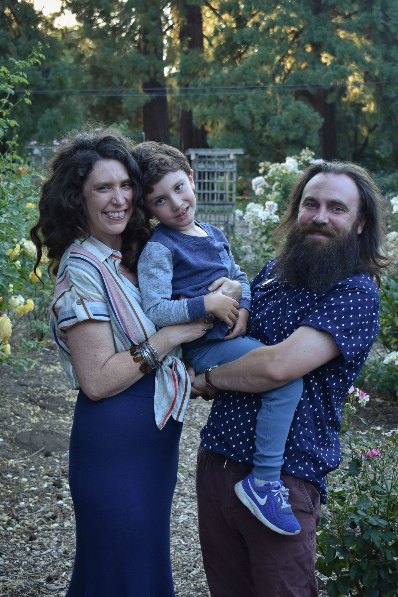 Family of three posing in flower garden for family pictures in Corvallis Oregon.
