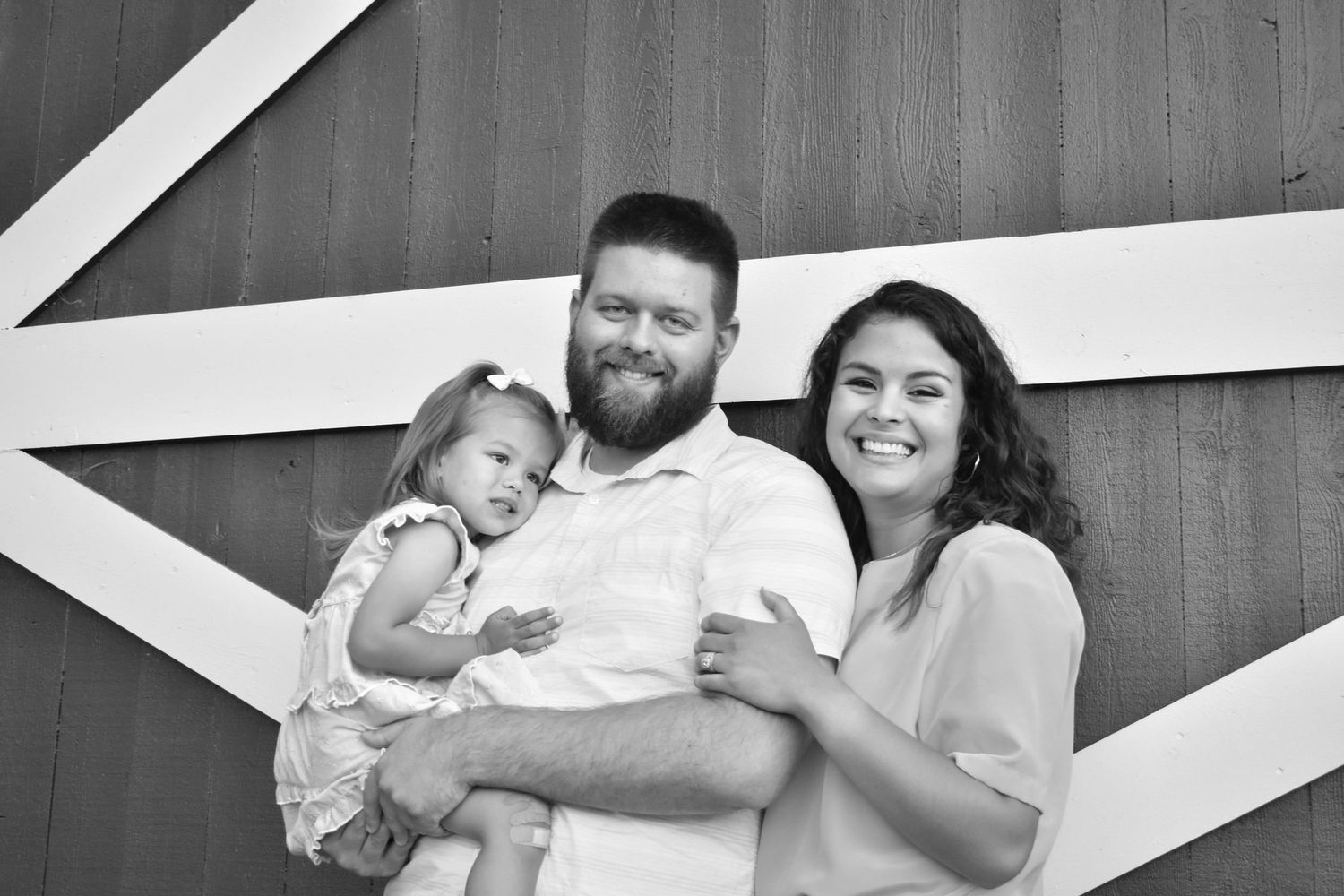 Black and white close up of family in front of a barn.