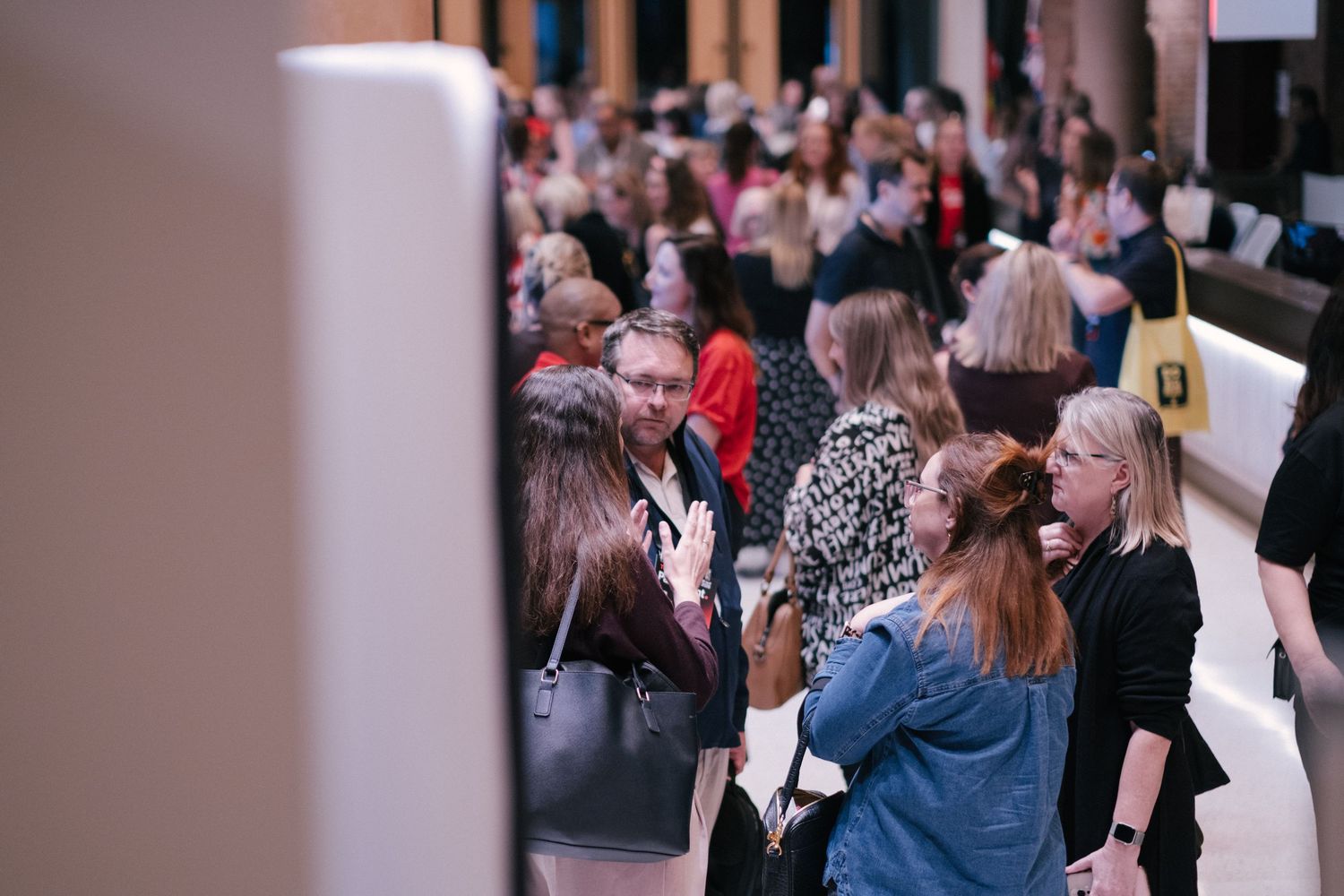 Busy crowd of attendees mingling and networking at a professional conference event.